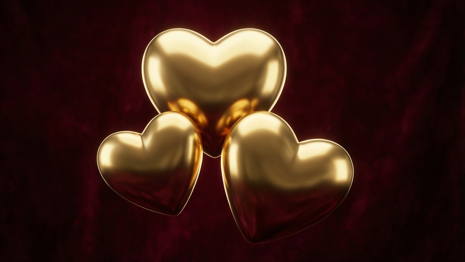 Gold Metallic Hearts 壁紙 — 三顆閃閃發光的金色心形漂浮在濃郁的勃艮第天鵝絨背景上，光線柔和。