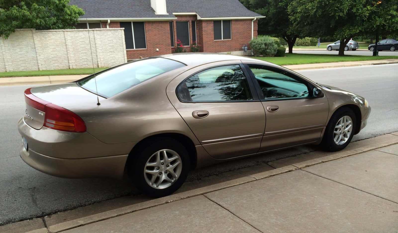 Dodge Intrepid 桌布 壁紙 — 一輛金色轎車停泊在住宅街道旁的行人路邊，背景有房屋和樹木。