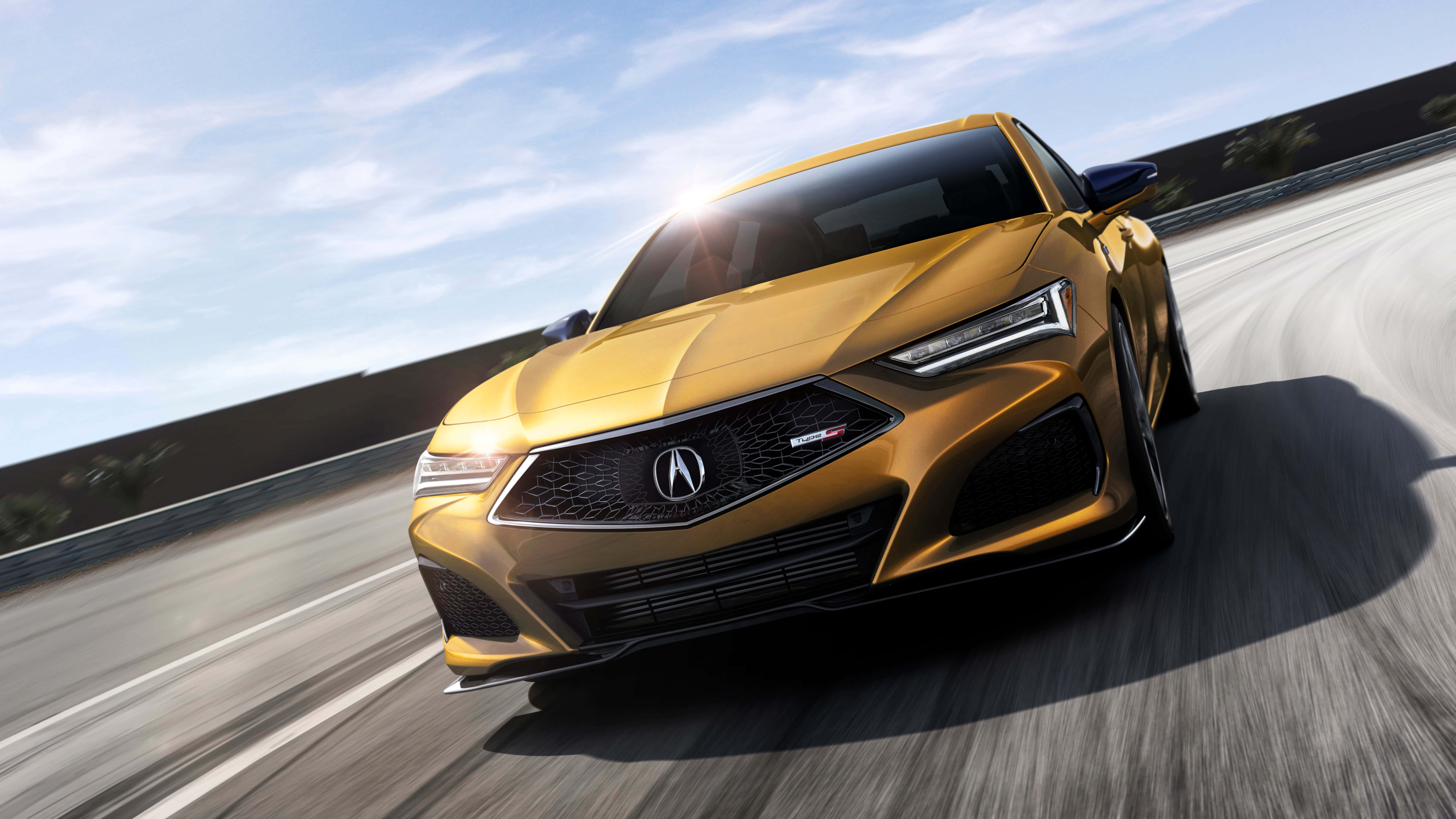 Acura Tlx 桌布 壁紙 — 一輛金色Acura跑車在陽光照耀的賽道上疾馳，動態模糊強調其速度。