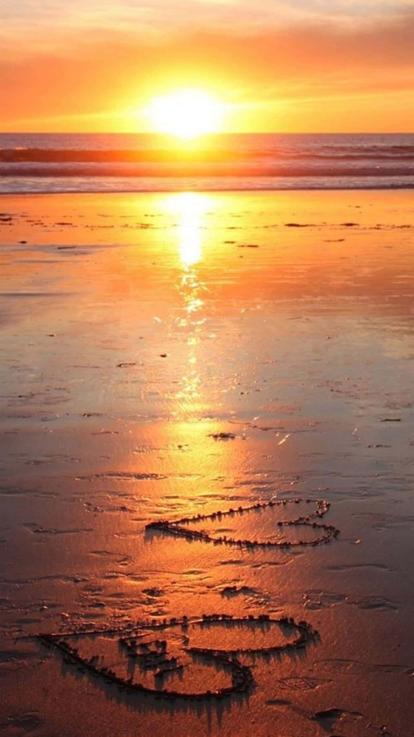 Coastal Sunset 桌布 壁紙 — 金色夕陽在濕漉漉的沙灘上投下溫暖的光芒，沙灘上畫的兩顆心反射出閃爍的光芒。