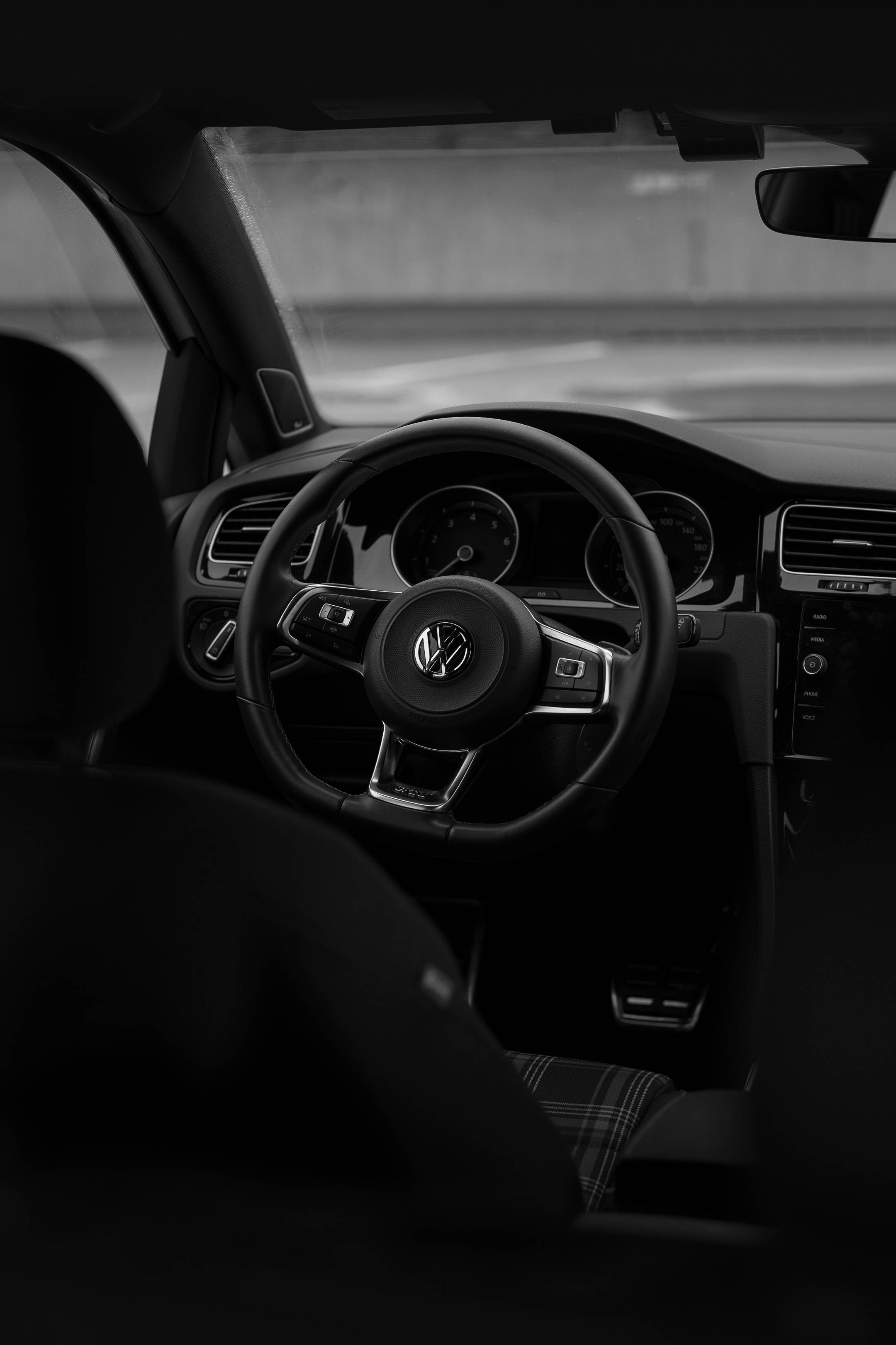 Golf GTI 方向盤特寫 壁紙 — 福士汽車駕駛艙的單色內部照片，聚焦於方向盤和儀表板。