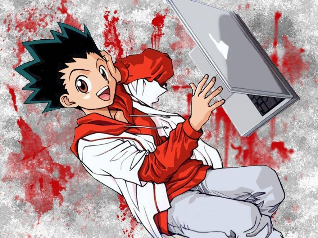 Gon Freecss 使用筆電壁紙 壁紙 — 動漫男孩穿著紅色連帽衫，高興地拿著筆記本電腦，背景是紅色和灰色的潑濺效果。
