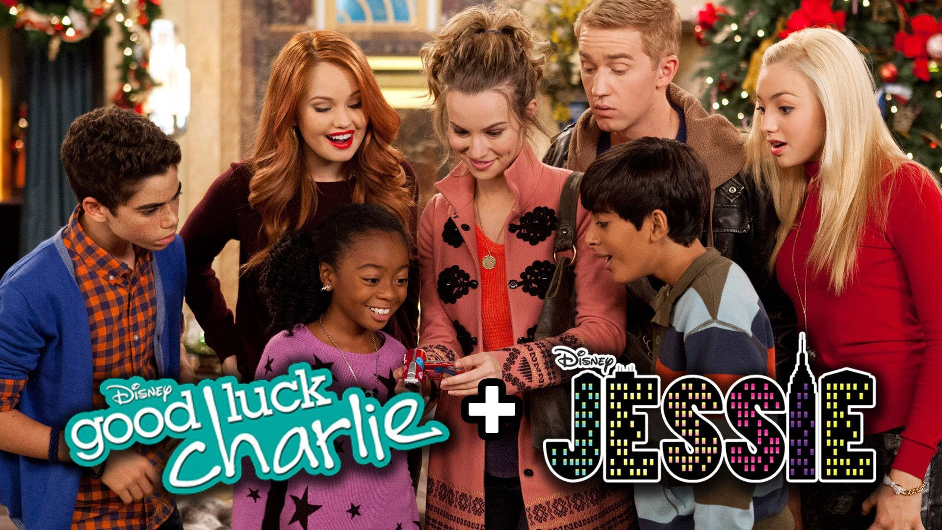 Good Luck Charlie 與傑西 壁紙 — 七位年輕演員穿著節日服裝，緊密圍繞著一個小禮物，在溫暖燈光的室內聖誕場景中微笑並表現出驚喜和喜悅。