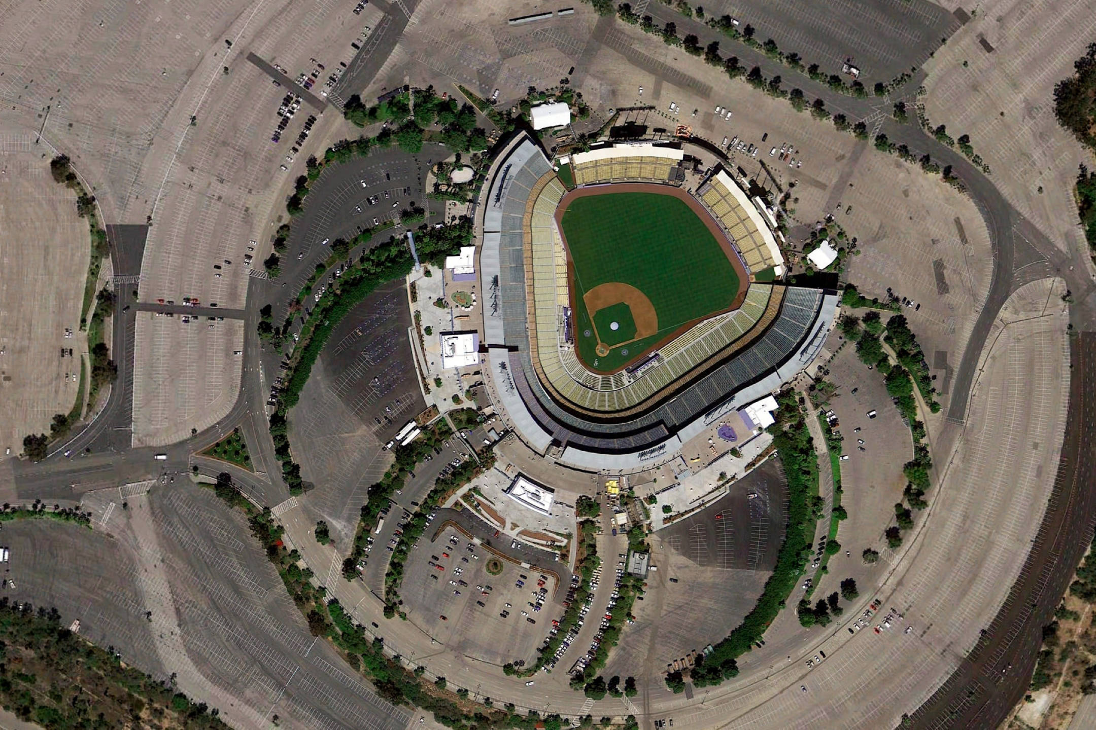 Google Earth 洛杉磯道奇球場 壁紙 — 晴朗日間，一個棒球場被廣闊停車場和道路環繞的鳥瞰圖。