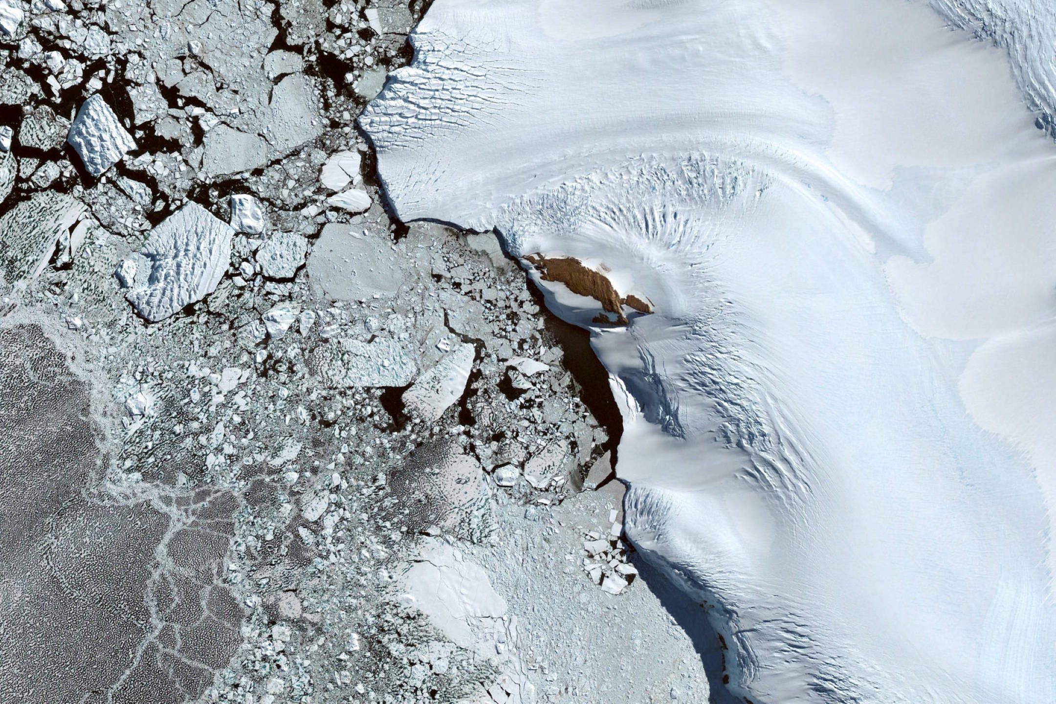 Google Earth 南極冰水區 壁紙 — 從高空俯瞰碎裂的冰層和平滑的冰川流，露出深色的水道。
