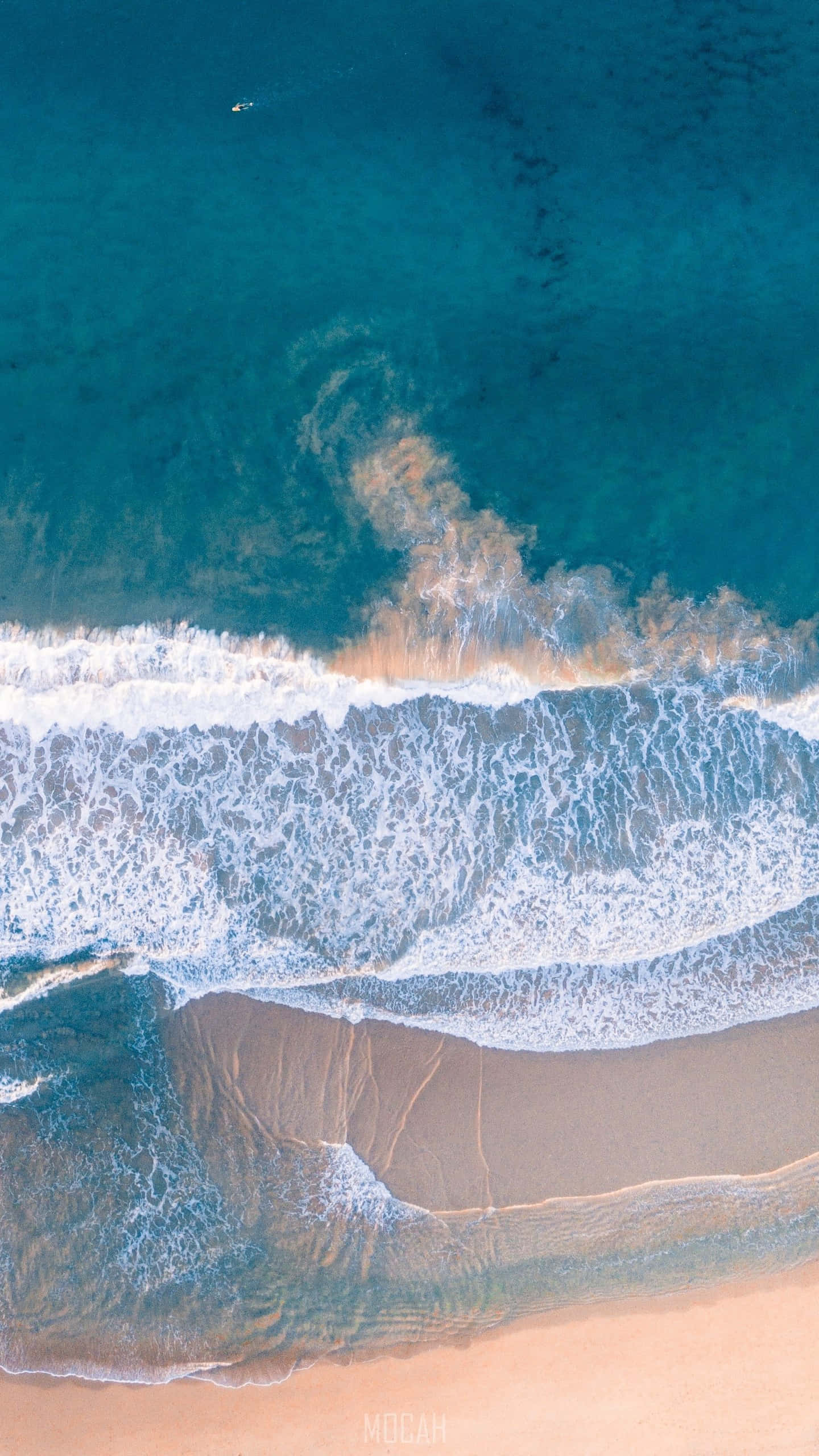 紅色開箱 Google Pixel XL 壁紙 — 從高空俯瞰，碧綠色的海浪拍打著金色沙灘，遠處有一個孤獨的泳者。