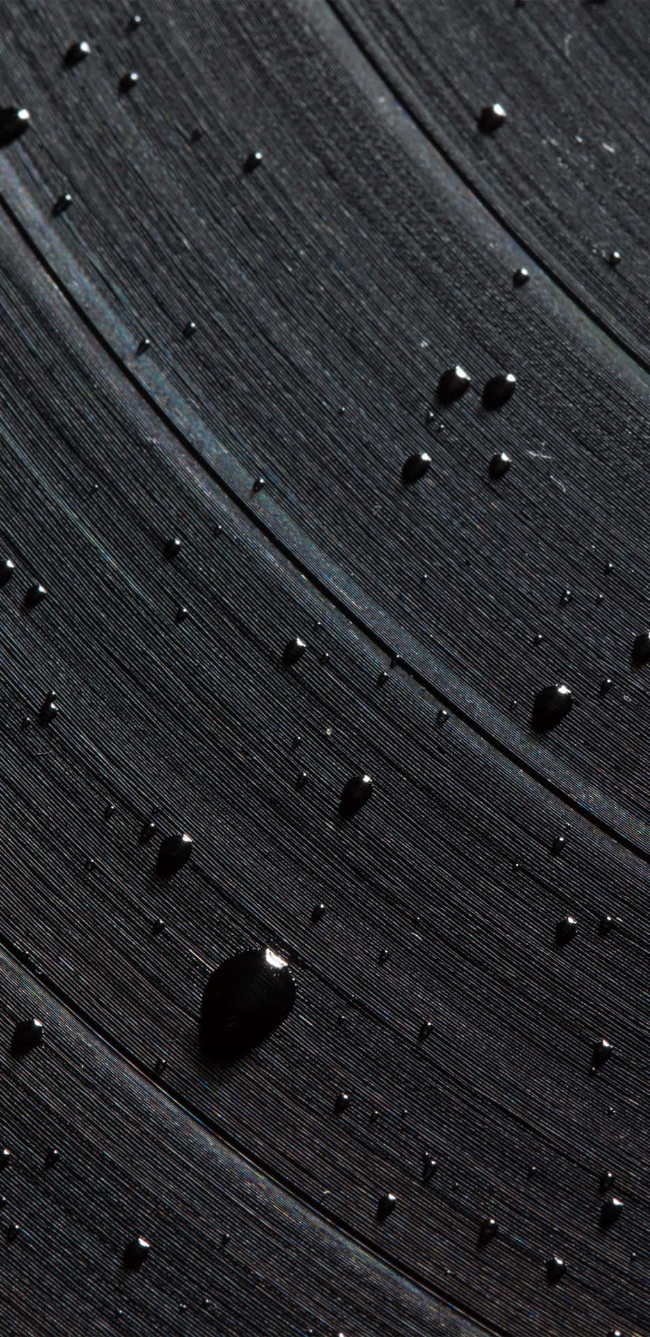 深色木質表面上的雨滴，帶有可見的木紋紋理。