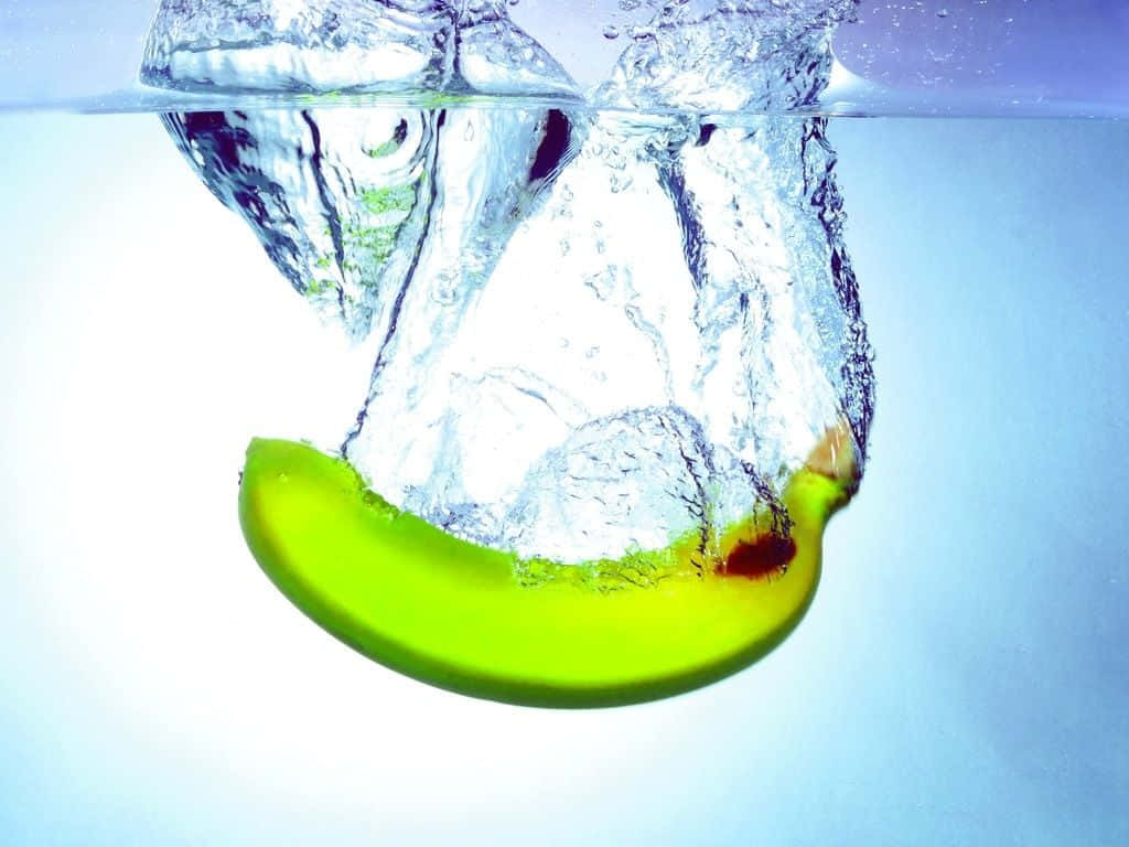 一片青蘋果片落入水中，帶有氣泡和漣漪。