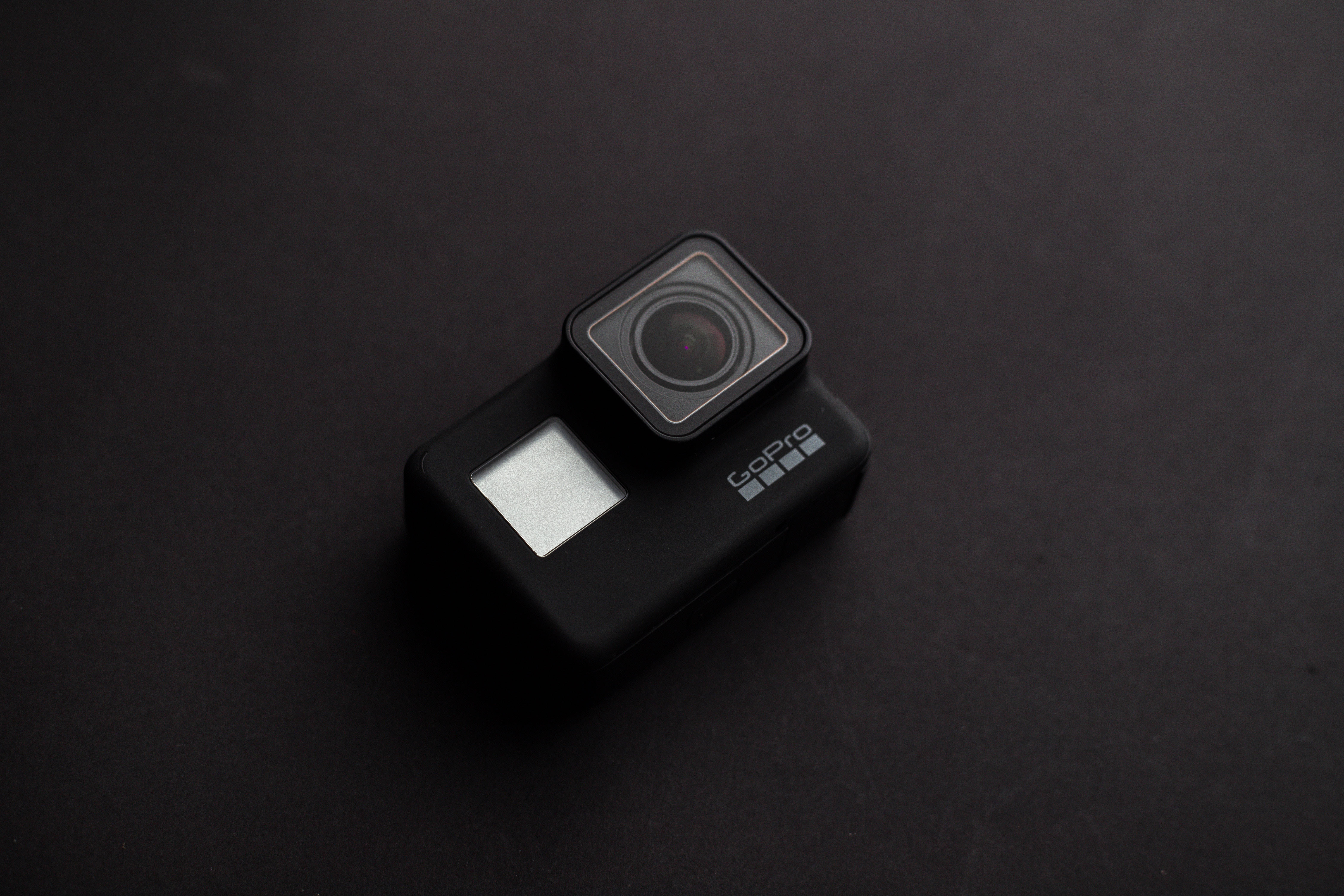 流線型黑色GoPro 壁紙 — 一部時尚的黑色GoPro相機在柔和的工作室燈光下放置在磨砂深色表面上。