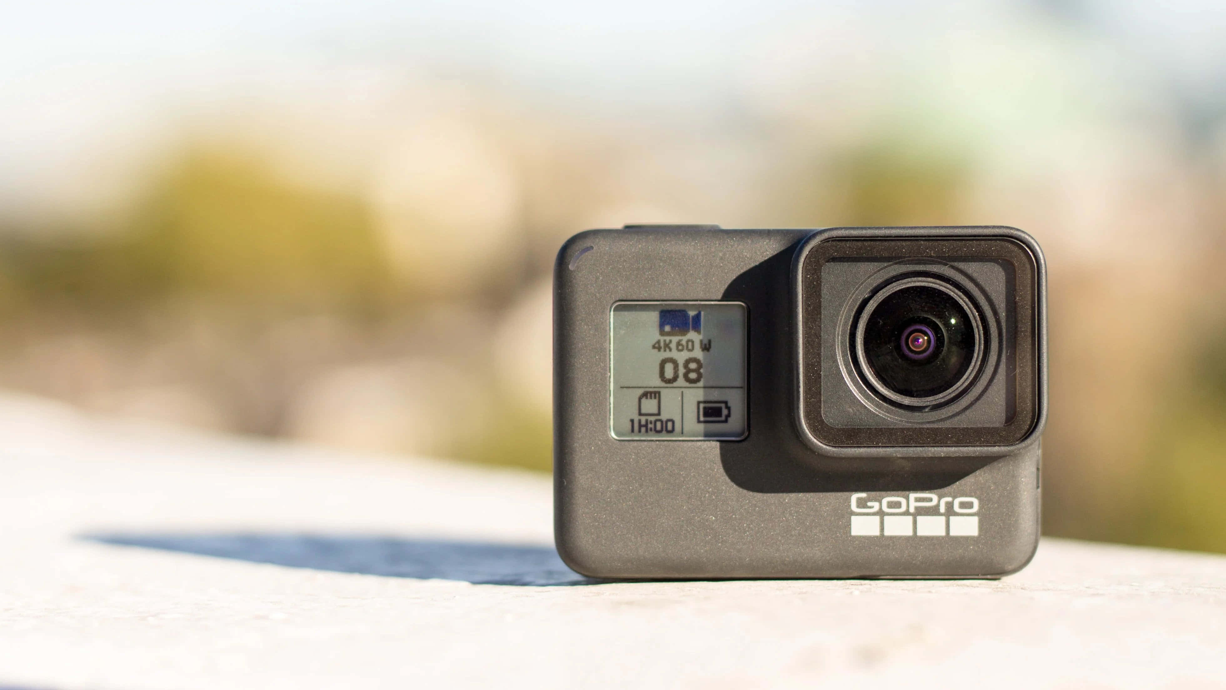 gopro 桌布 壁紙 — GoPro 運動相機放置在陽光照射的表面上，背景模糊自然。