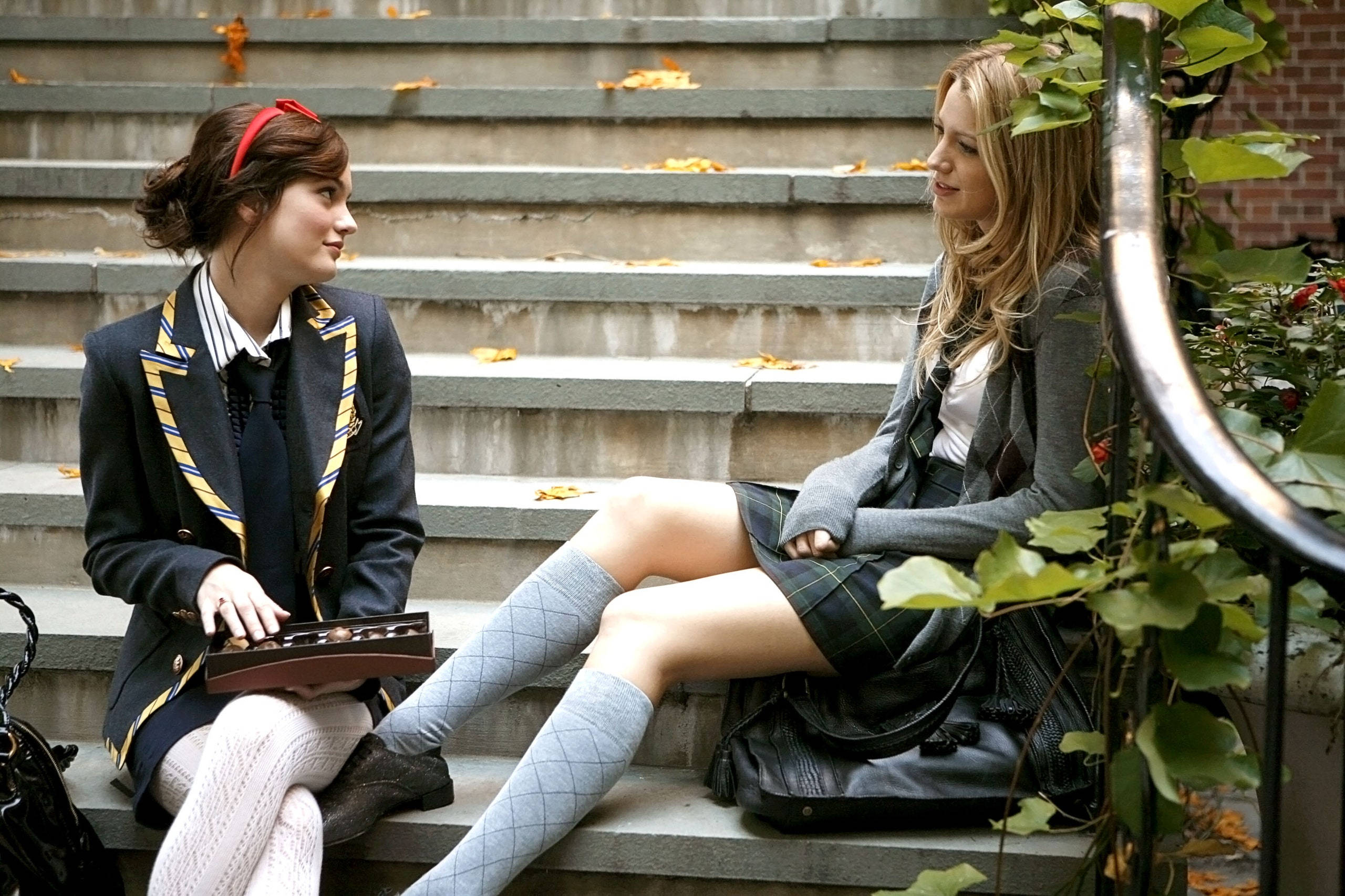 《Gossip Girl》布萊爾與塞雷娜樓梯合影 壁紙 — 兩名身穿校服的女生坐在混凝土台階上，周圍是落葉和綠色藤蔓。