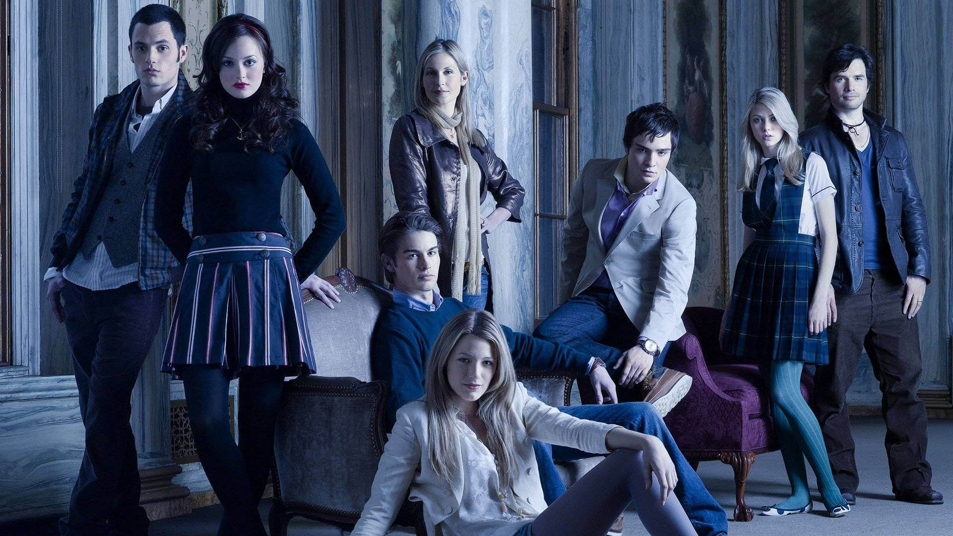 Gossip Girl 美學群像 壁紙 — 七位穿著時尚的年輕人在一個擁有古典柱子和復古家具的宏偉華麗房間中自信地擺姿勢。