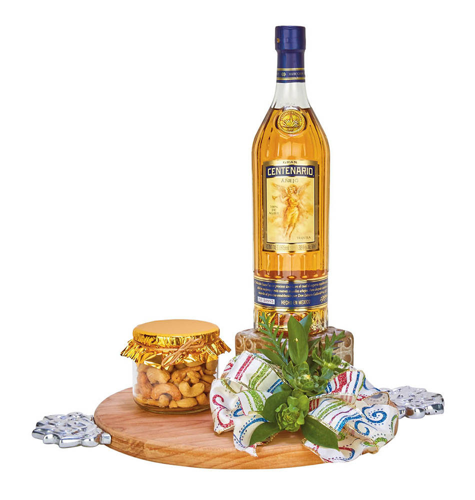Centenario tequila酒瓶搭配腰果和裝飾性綠植在木板上。