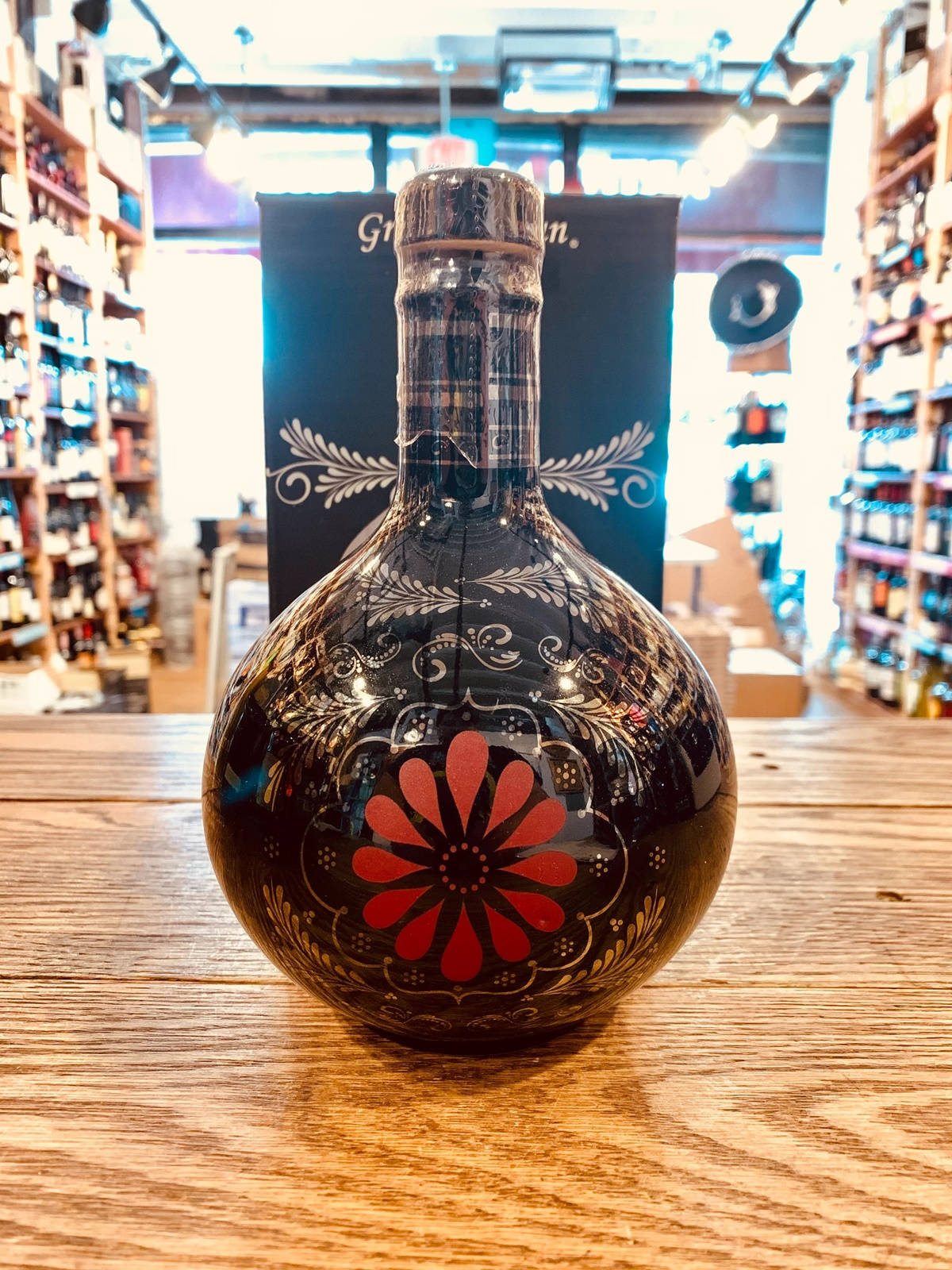 酒類商店木製櫃檯上帶有紅色花朵的裝飾性黑色瓶子。