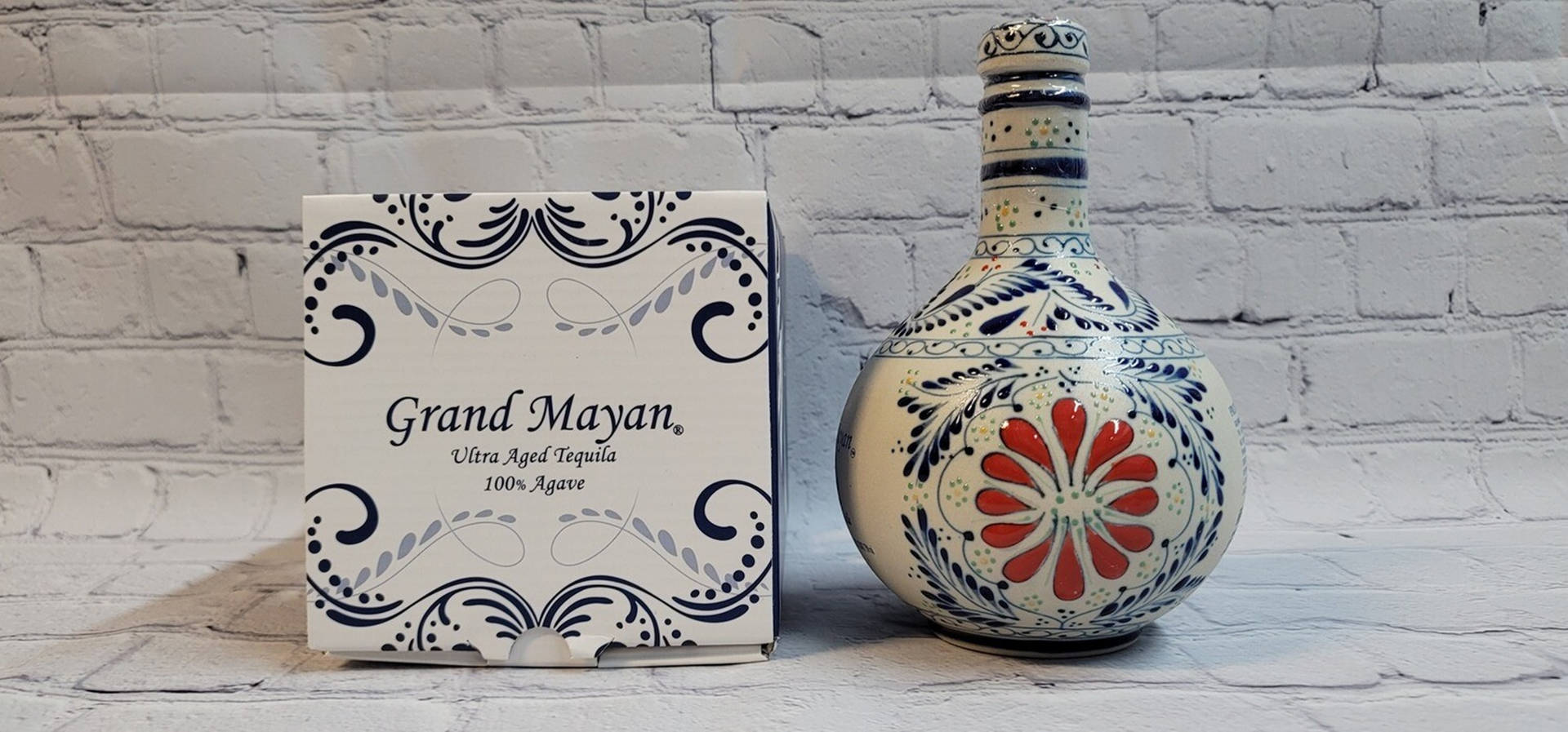 Grand Mayan 龍舌蘭酒瓶和盒子在白色磚背景上