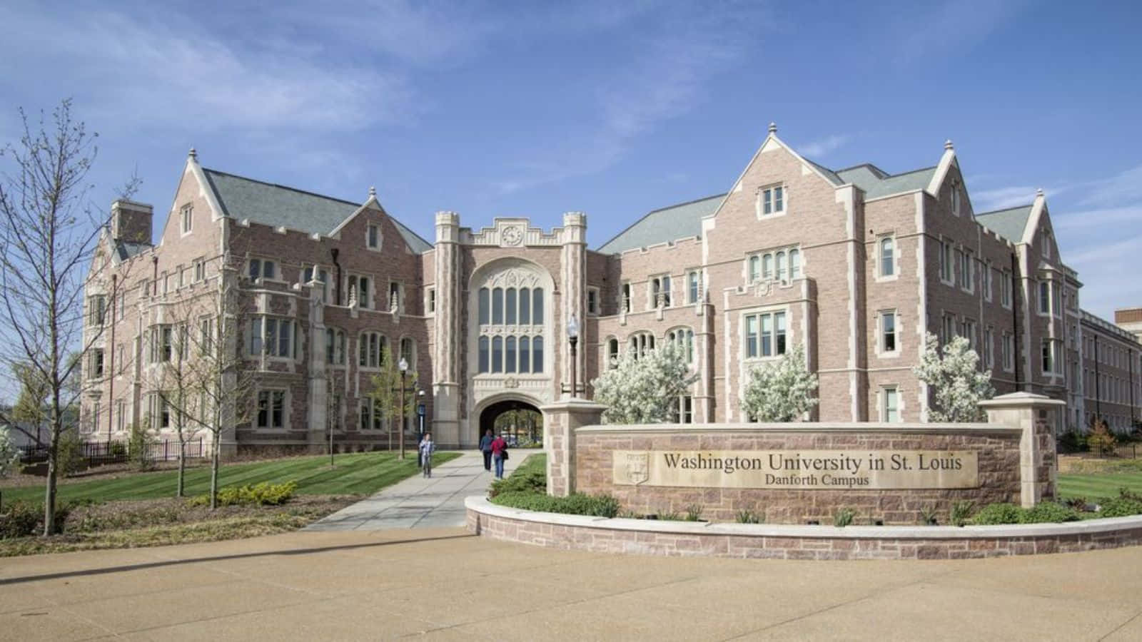  壁紙 — 大型石造大學建築，設有拱形入口及修剪整齊的場地，在清澈藍天下。