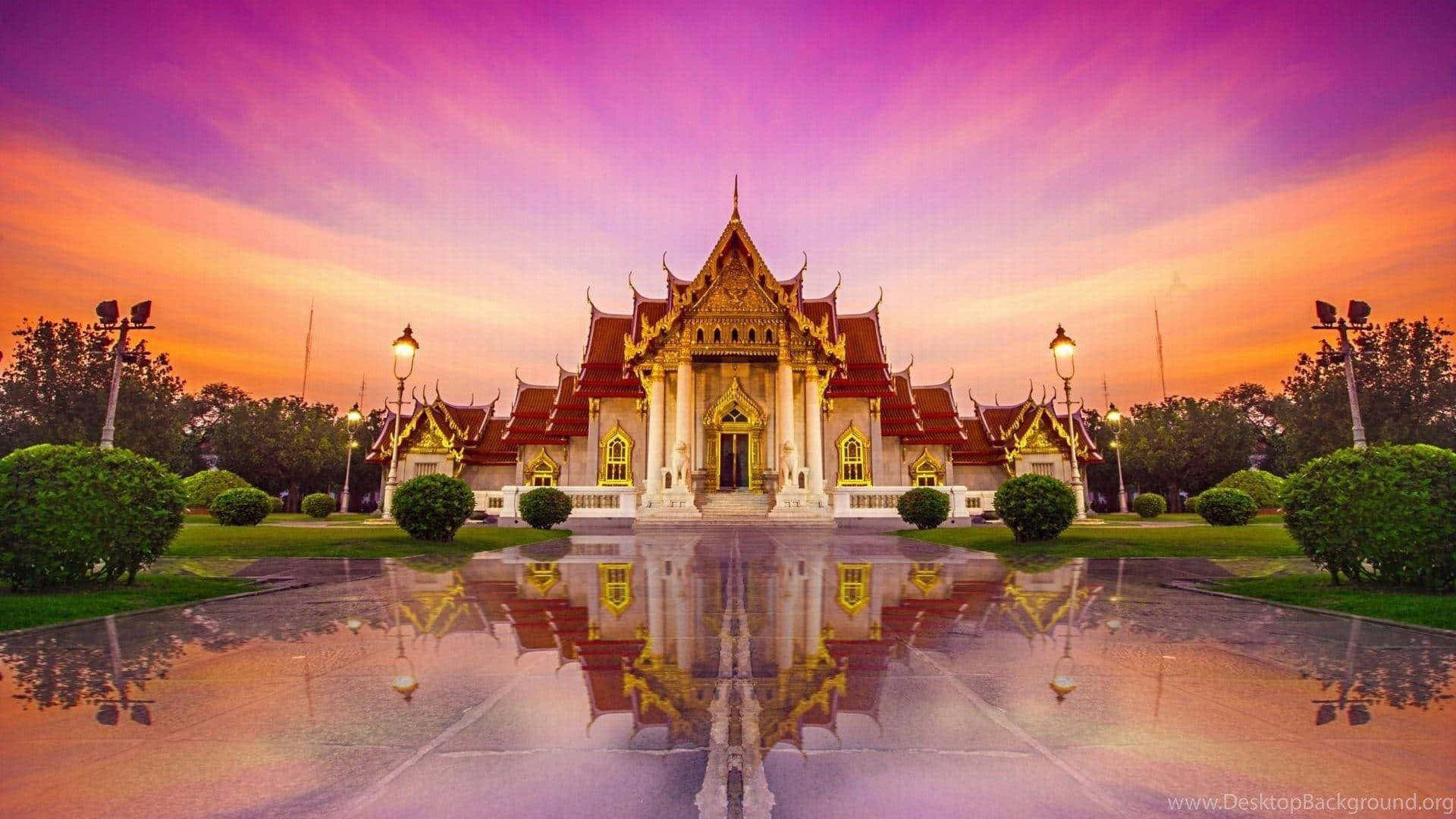  壁紙 — 一座宏偉的泰國寺廟，金色尖塔在潮濕的路面上完美倒映，背景是充滿活力的紫色和橙色日落天空。