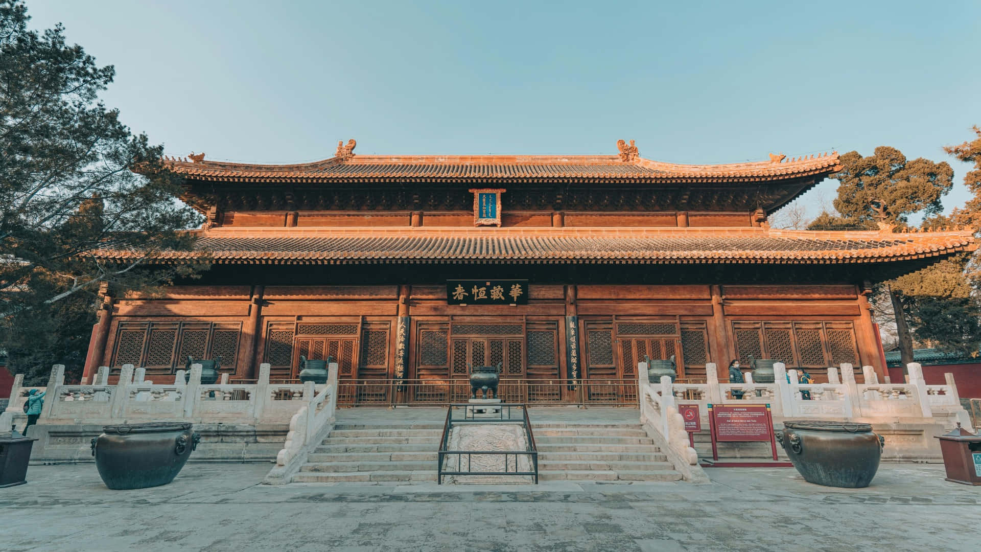  壁紙 — 一座宏偉的傳統中式木造寺廟，擁有寬闊的瓦頂和石階，在清澈的藍天下。