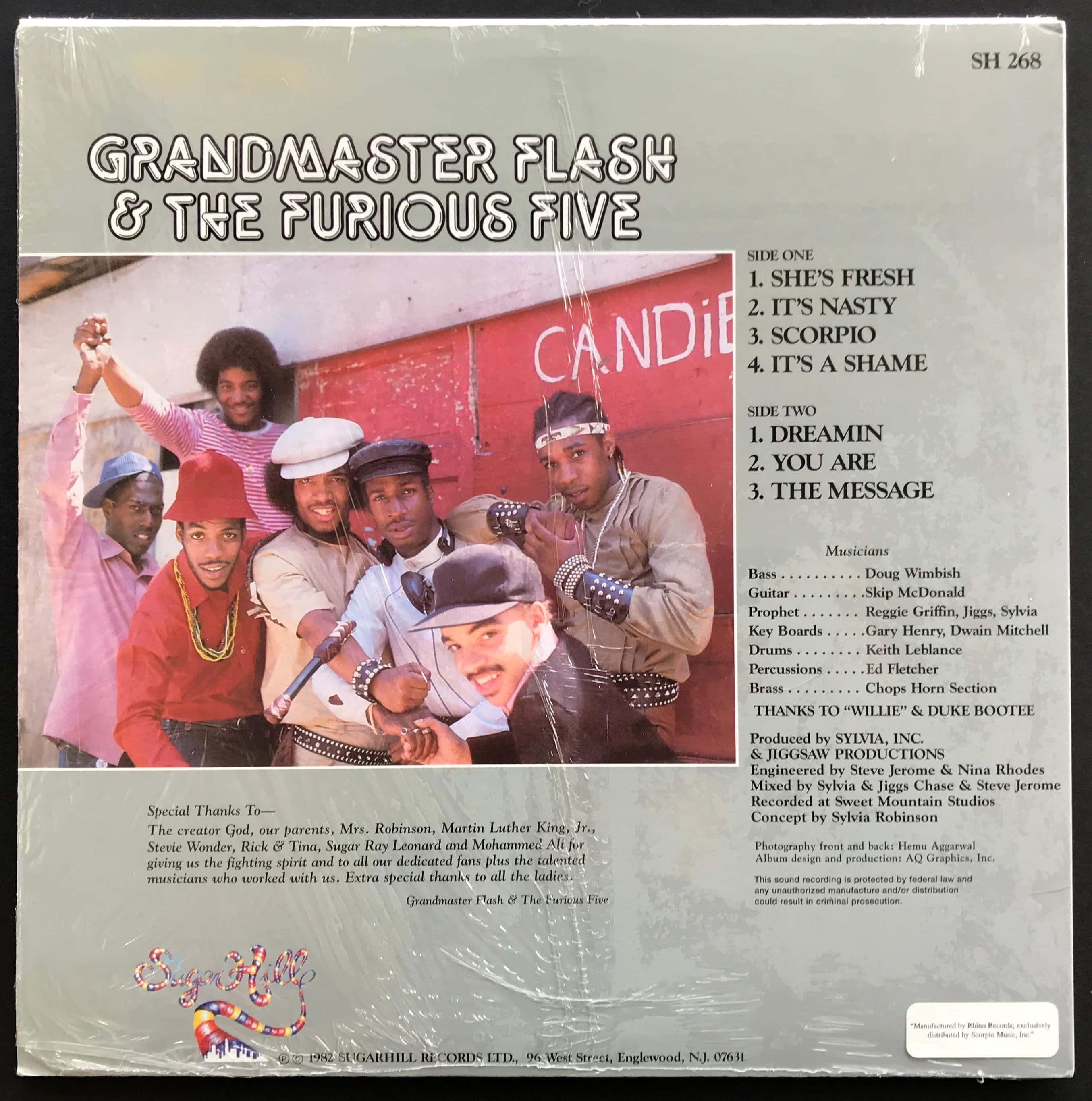 Grandmaster Flash 和 The Furious Five 的經典形象 壁紙 — Grandmaster Flash 和 The Furious Five 在復古專輯封面上，於紅色糖果店牆前充滿活力地擺姿勢。