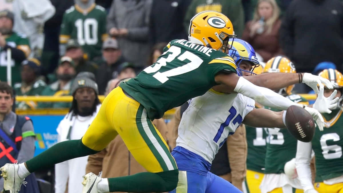  壁紙 — 綠灣包裝工隊的防守球員在激烈的NFL美式足球比賽中跳起擒抱達拉斯牛仔隊的接球員。
