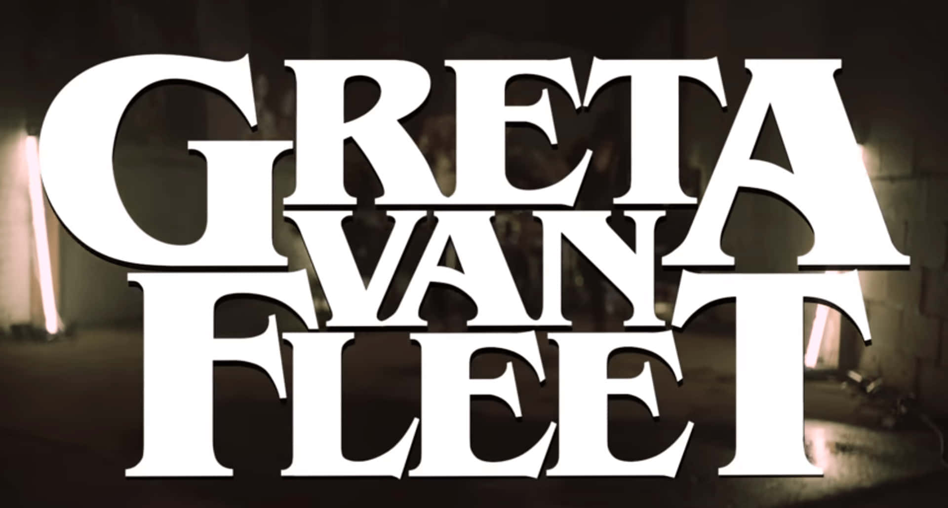 Greta Van Fleet 樂隊名稱以粗體白色字母顯示在黑暗的工業背景上，帶有發光的燈光。