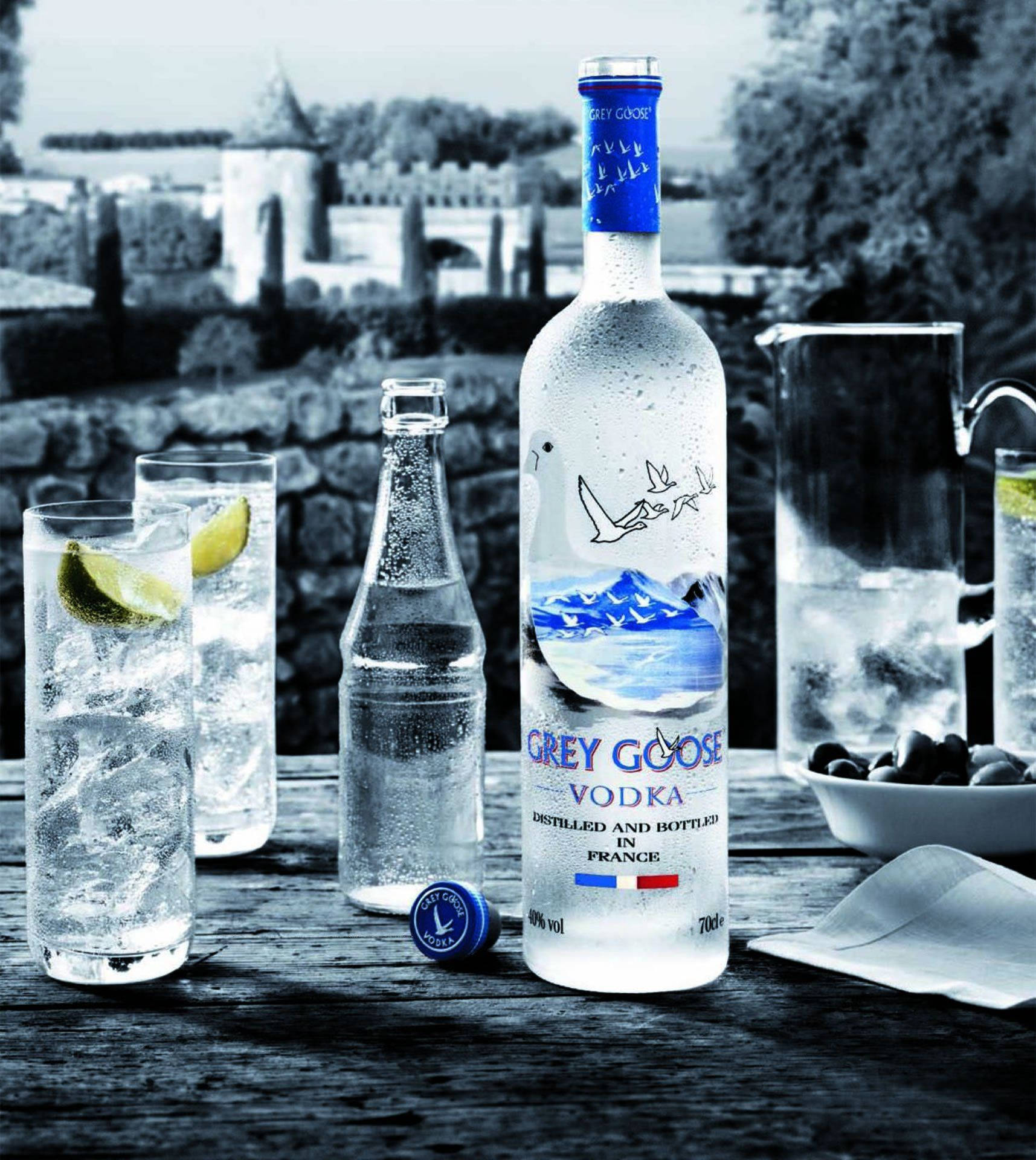 Grey Goose伏特加酒瓶，附有冰飲和橄欖，放在城堡附近的木桌上。