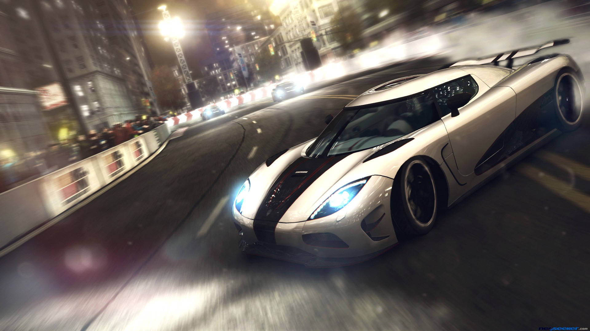 Grid 2 動態賽事 壁紙 — 一輛銀色 Koenigsegg 超級跑車在夜間穿過霓虹燈閃爍的城市街道，帶有動態模糊和發光的車頭燈。