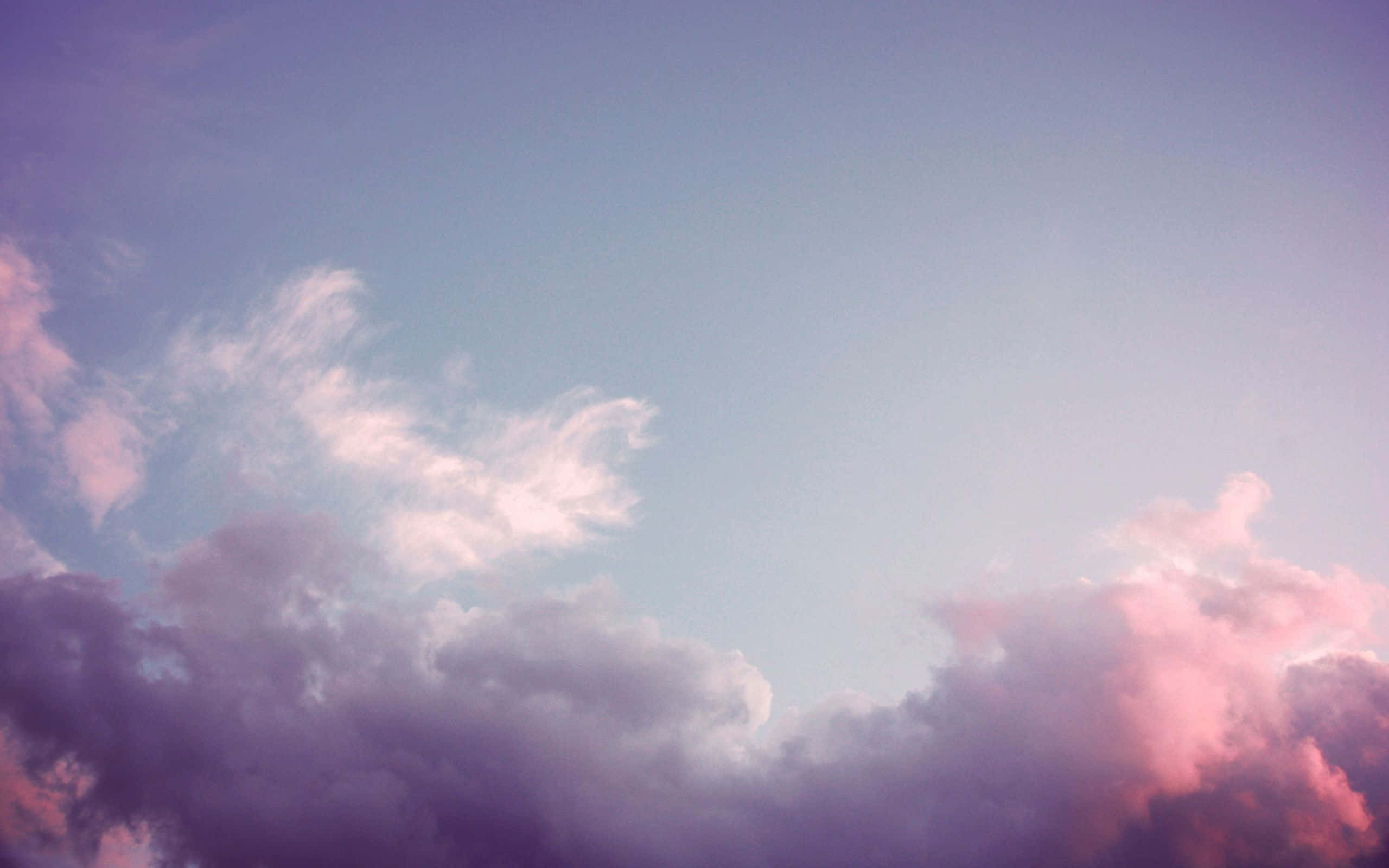 展現你的創意一面：Grunge Pink Aesthetic 筆記本電腦 壁紙 — 柔和的粉彩雲朵飄過以溫柔粉紅、紫色和藍色繪製的暮色天空。
