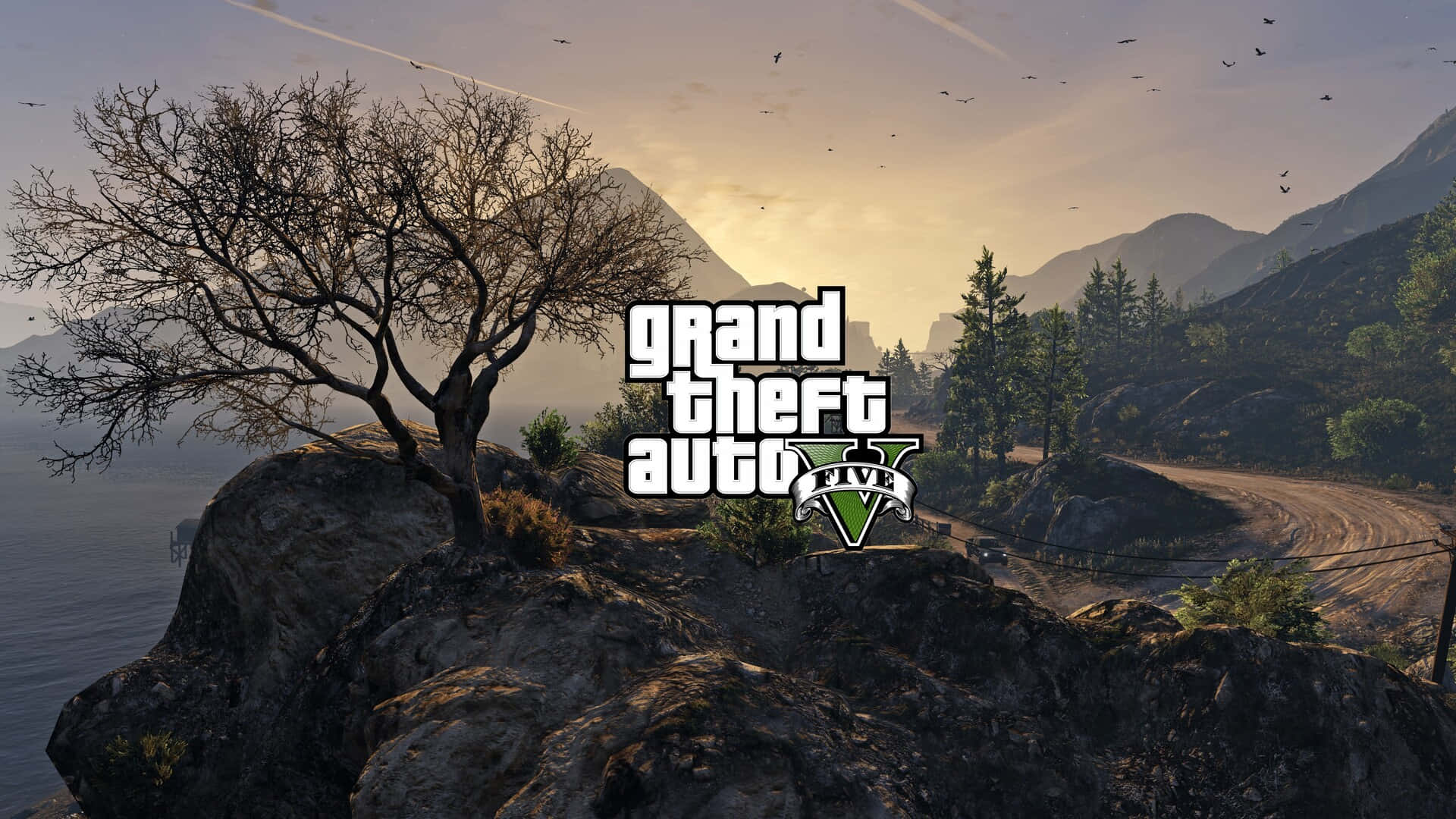 GTA V 標誌覆蓋在日落山景上，有一棵禿樹和蜿蜒的道路。