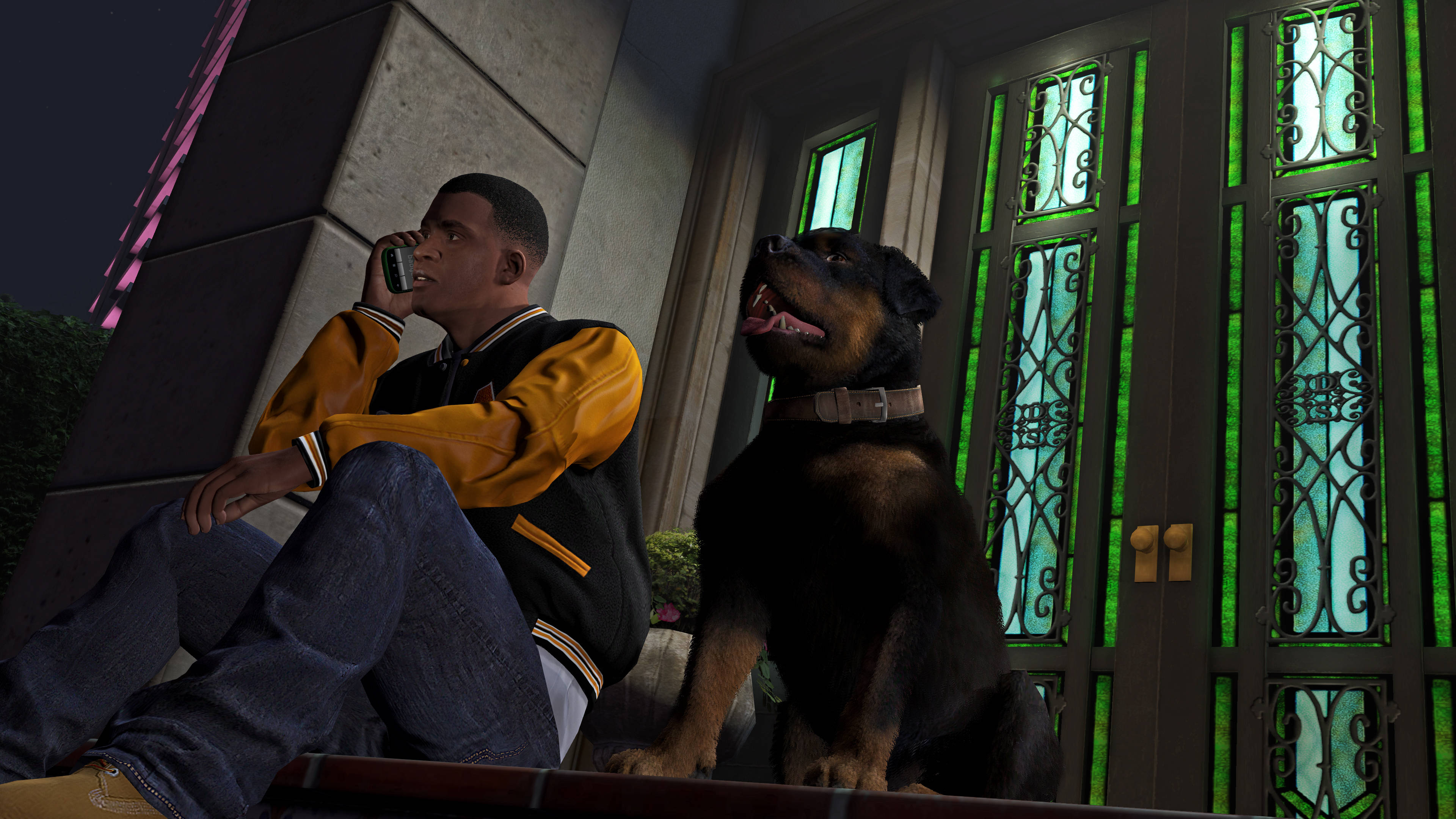 GTA V 最佳拍檔門前休憩 壁紙 — 一名身穿黃黑外套的男子在夜間於一棟有綠色玻璃門的建築物外的長椅上，與一隻警覺地坐著的洛威拿犬旁邊通電話。