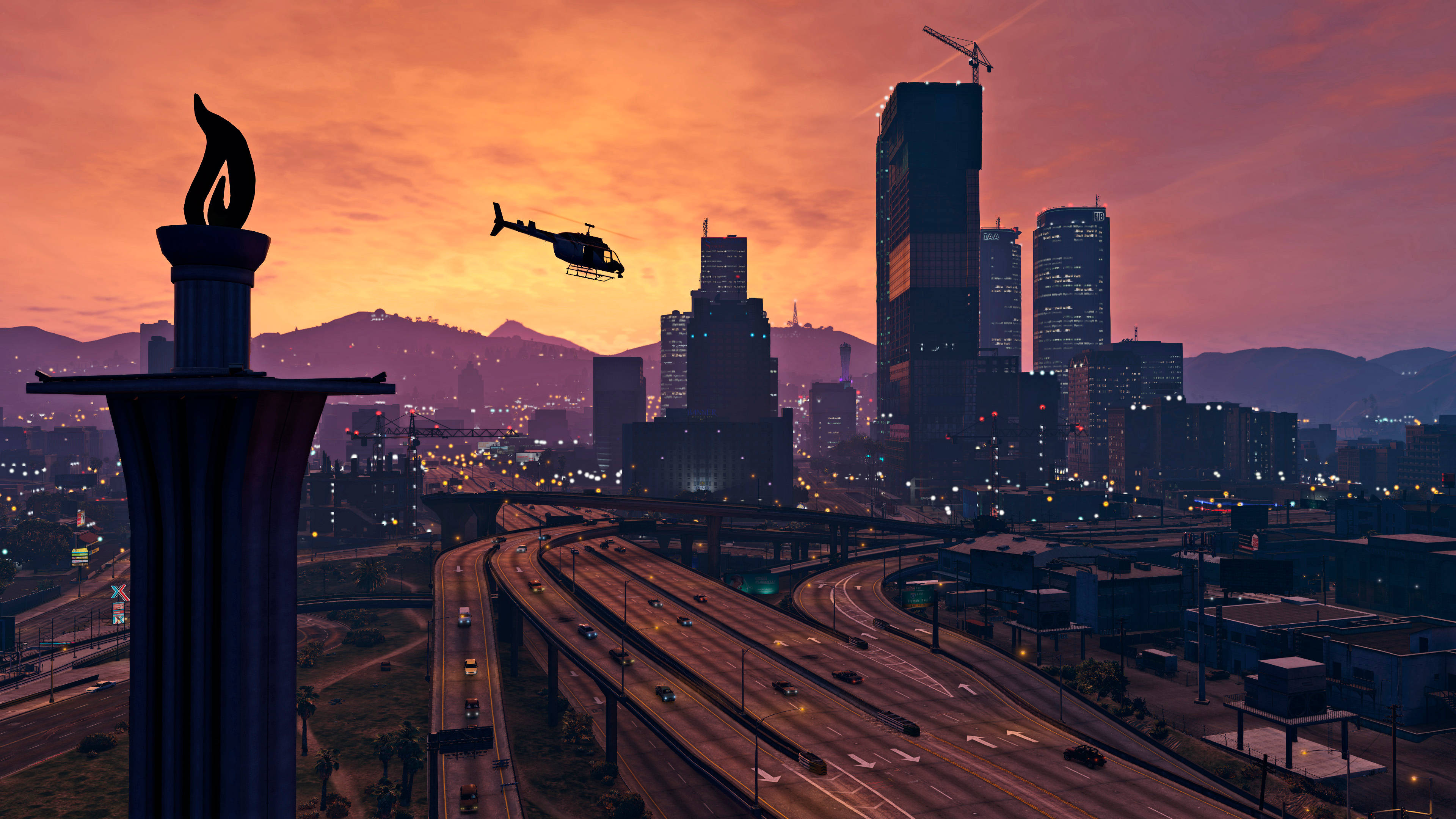 GTA V 洛聖都高速公路 壁紙 — 一架直升機在日落時分飛過廣闊的城市景觀，閃爍的摩天大樓和蜿蜒的高速公路。