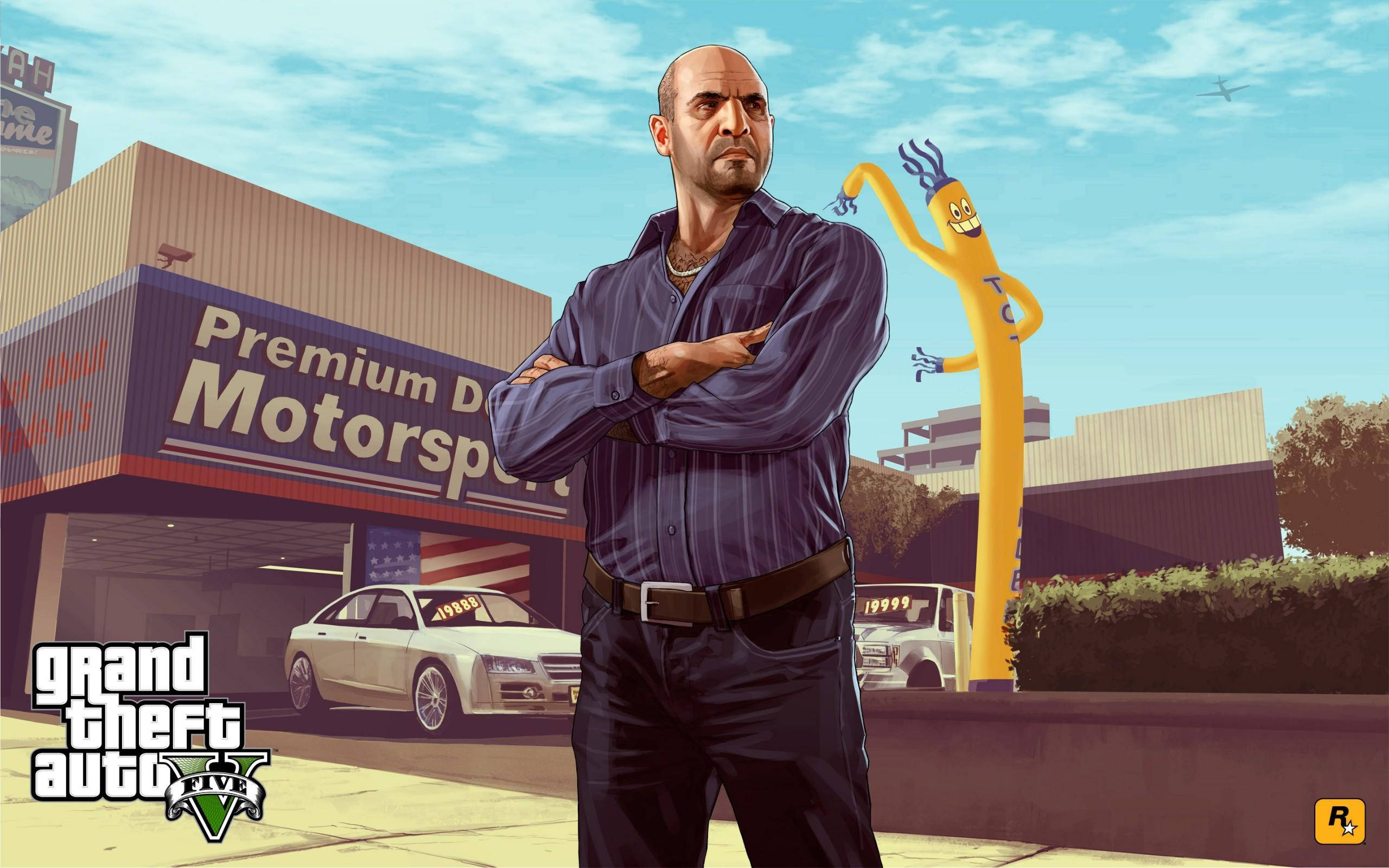 GTA V 車商西蒙 壁紙 — 一個光頭男人穿著藍色襯衫，雙臂交叉站在「Premium Motorsport」經銷商外面，有一個黃色充氣吉祥物和一輛白色跑車，在明亮的藍天下。