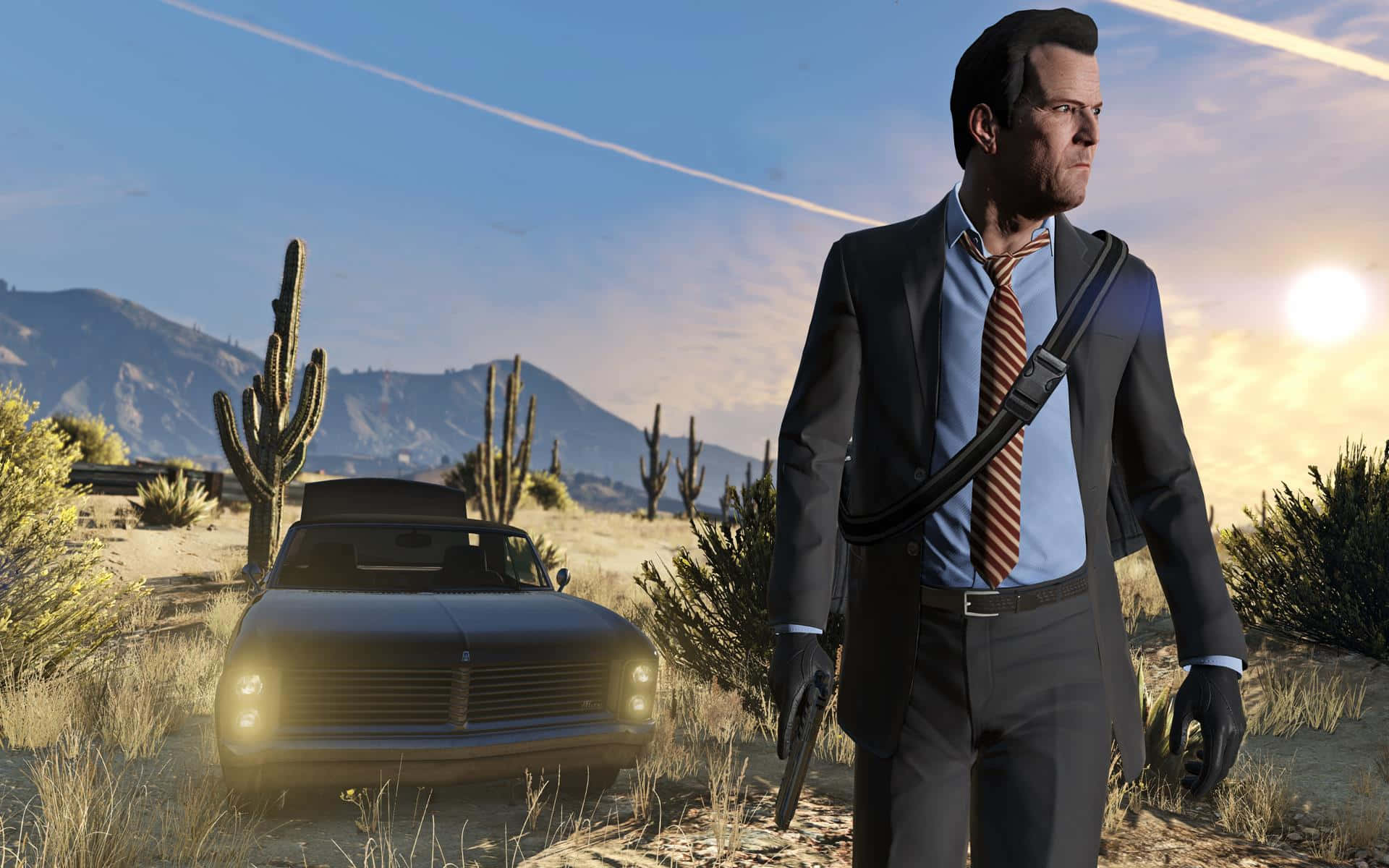 GTA沙漠持槍角色圖 壁紙 — 一名身穿西裝的男子在陽光明媚的沙漠中，伴隨著仙人掌和山脈，在清澈的藍天下走在一輛老爺車旁邊。
