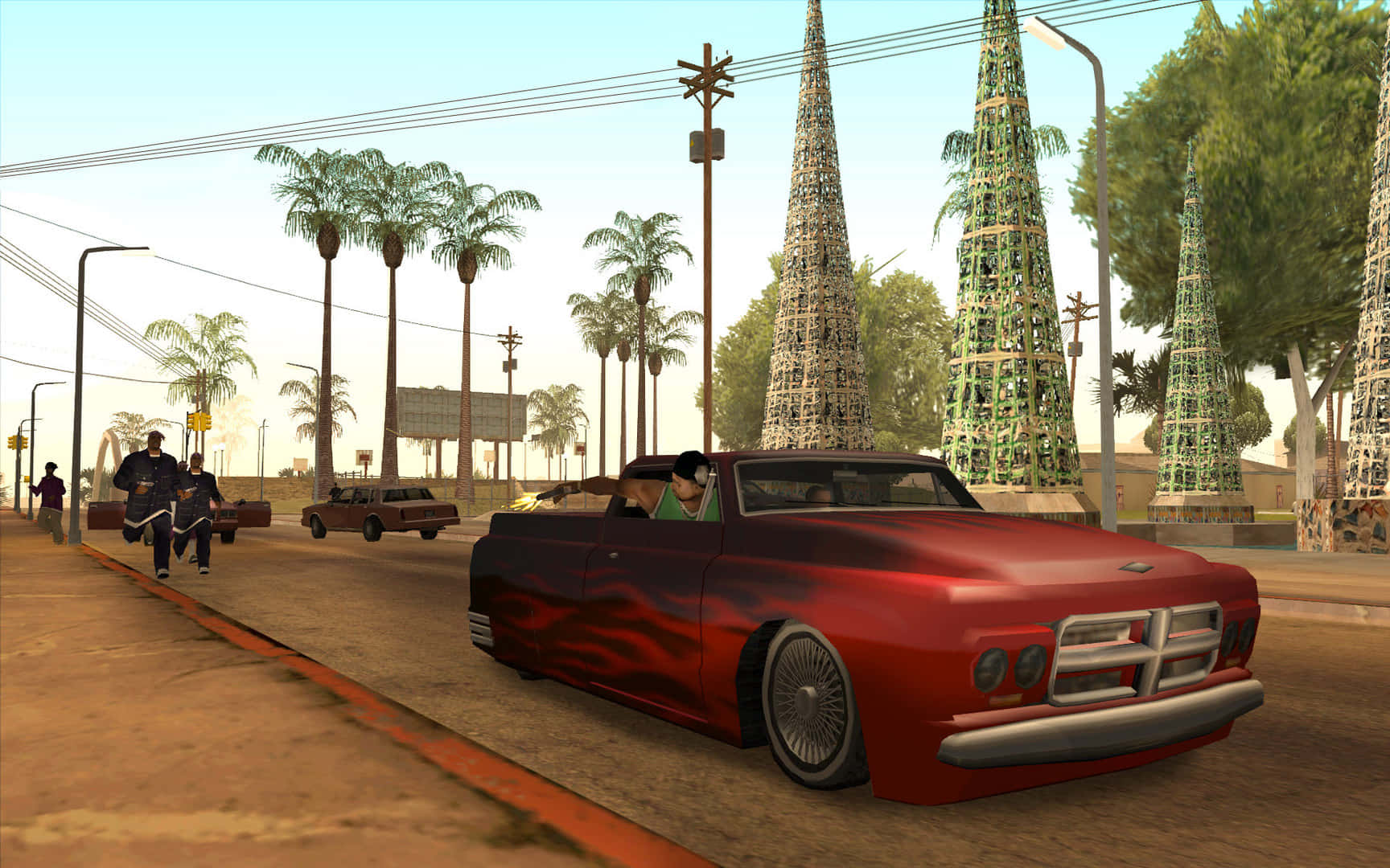 GTA遊戲極致動作畫面 壁紙 — 一架紅色火焰塗裝的經典汽車在棕櫚樹成蔭的街道上行駛，經過高聳裝飾的聖誕樹，天空晴朗。