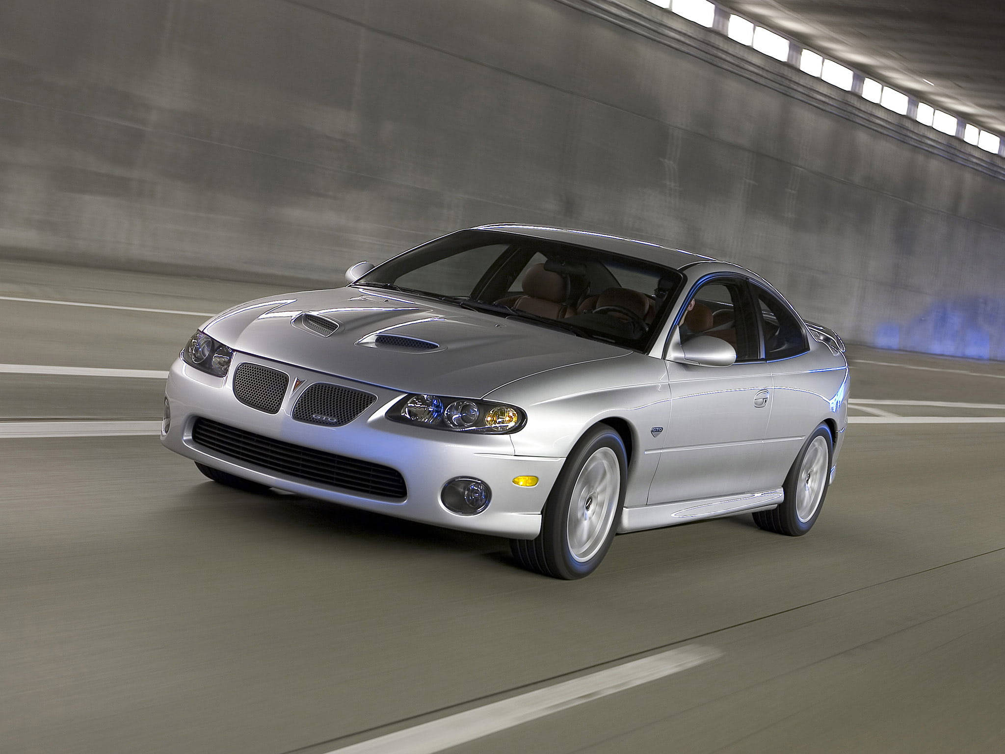 經典銀色龐蒂克GTO風采盡顯 壁紙 — 一輛銀色 Pontiac Grand Prix GXP 在混凝土隧道中高速行駛，路上呈現動態模糊效果。
