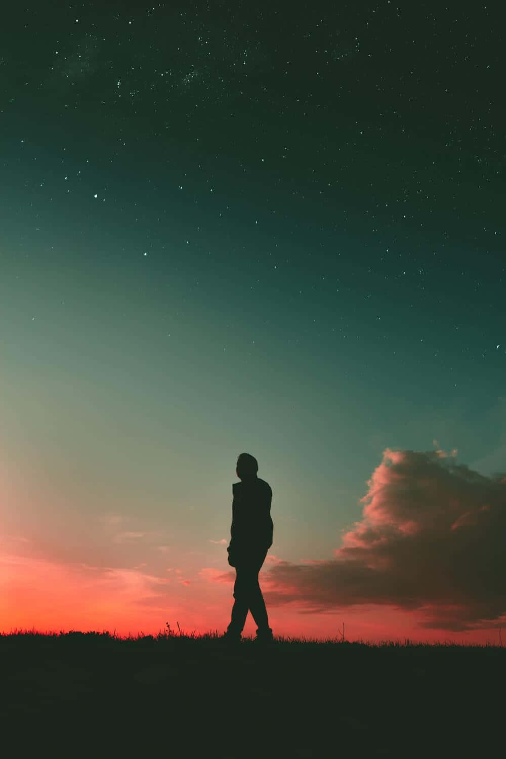 Sunset Silhouette 桌布 壁紙 — 一個孤獨的身影在青草覆蓋的山丘上行走，下方是星空暮色天空，塗上青綠色和火橙色的漸變。