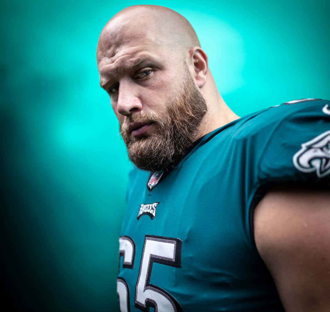  壁紙 — 一名光頭鬍鬚的足球員身穿青綠色Eagles球衣，在模糊的青綠色背景下凝視著。