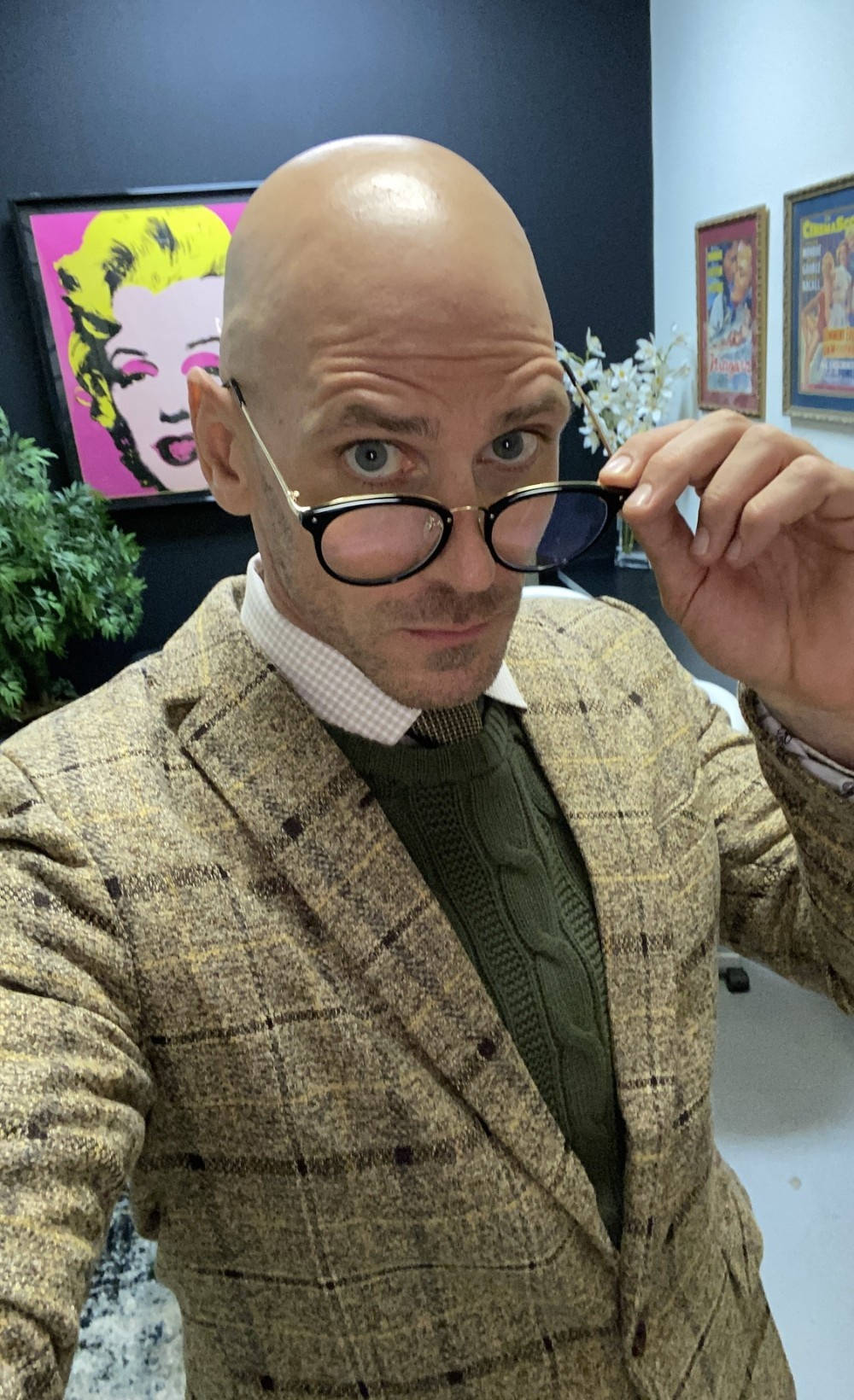 穿著格仔西裝外套的男人在充滿藝術氣息的辦公室裏拿着太陽眼鏡。