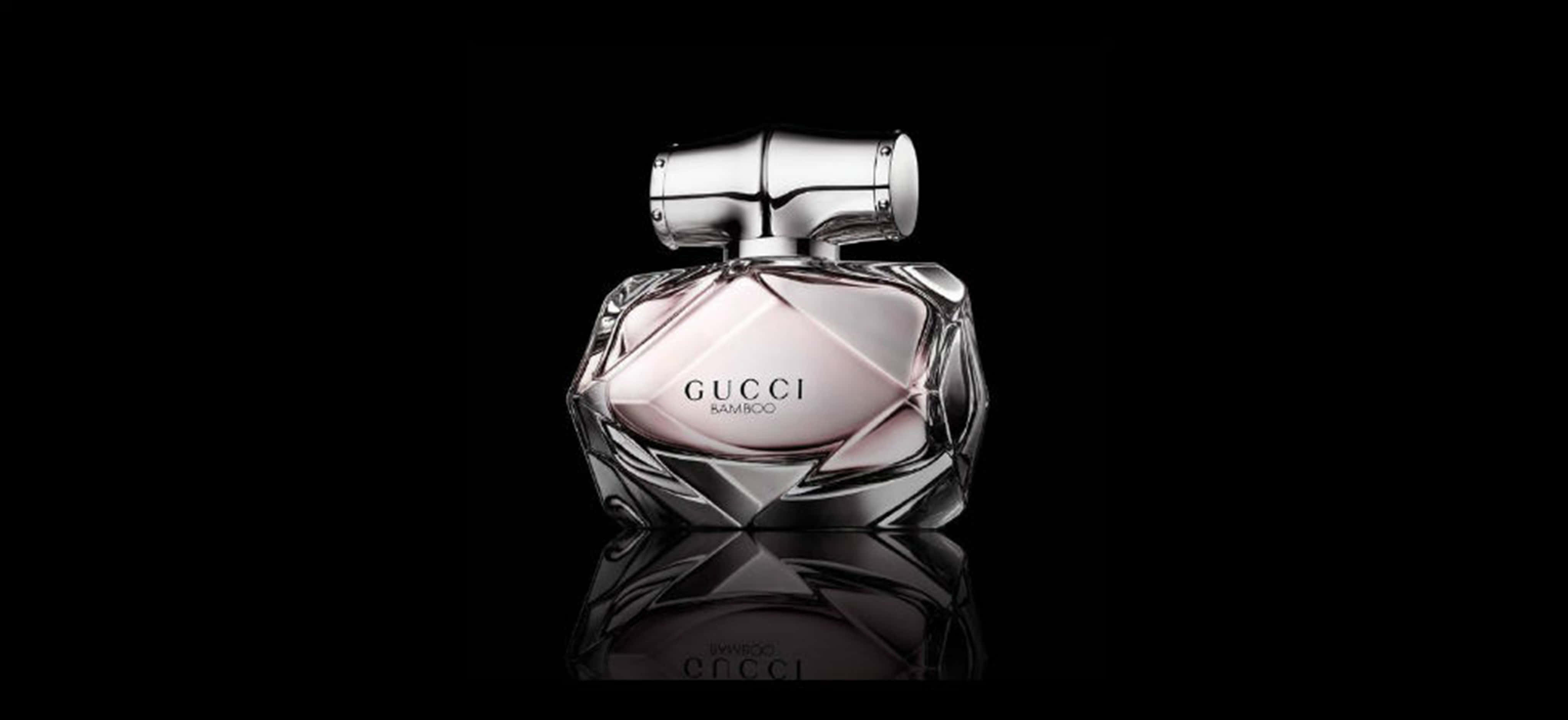 Gucci Bamboo香水4K 壁紙 — 一款時尚的Gucci Bamboo香水瓶，採用多面玻璃設計和銀色瓶蓋，在黑色背景上柔和發光。