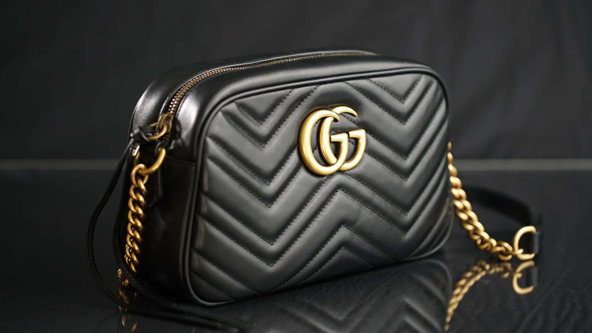 黑色絎縫Gucci手袋，金色鏈條肩帶，反射表面。