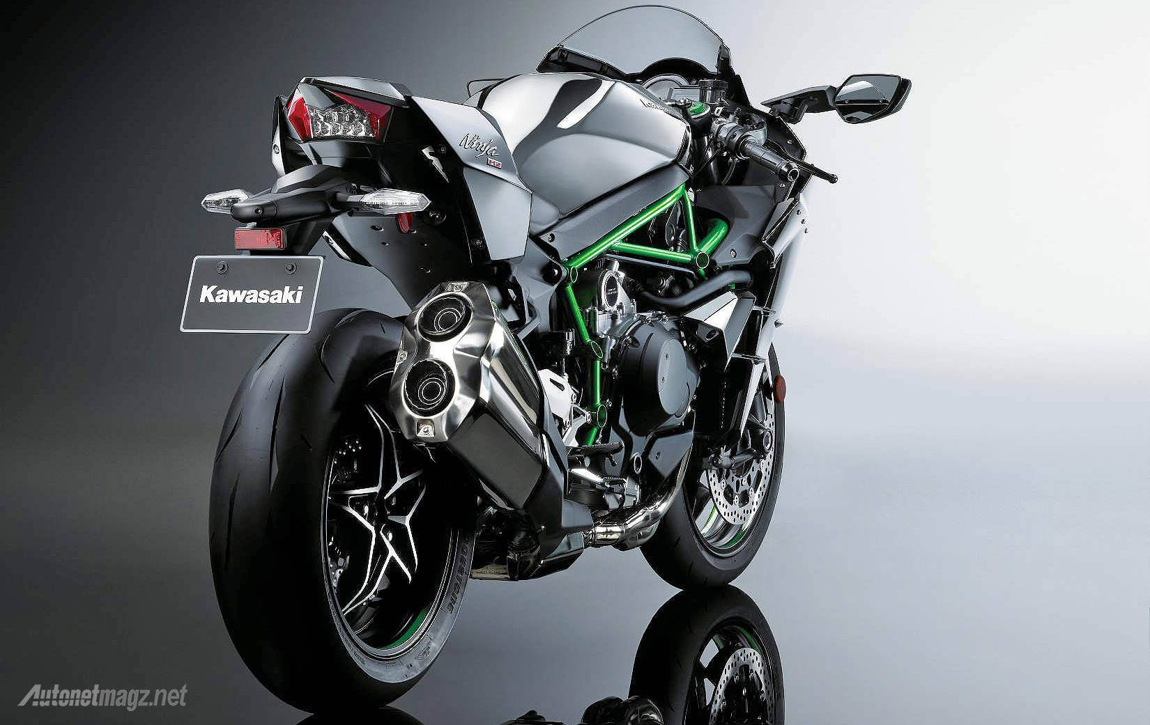 川崎H2R後視圖 壁紙 — 一輛時尚的銀綠色 Kawasaki Ninja 電單車，配備鍍鉻排氣管和黑色輪胎，在漸變灰色背景前傾斜放置在反光工作室地板上。