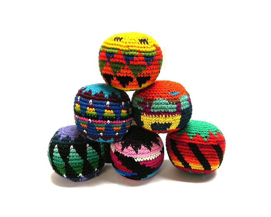 繽紛形狀編織Hacky Sack 壁紙 — 鮮豔的手工鉤針編織球，帶有鮮明的幾何圖案，堆疊成金字塔形狀，置於潔白背景上。