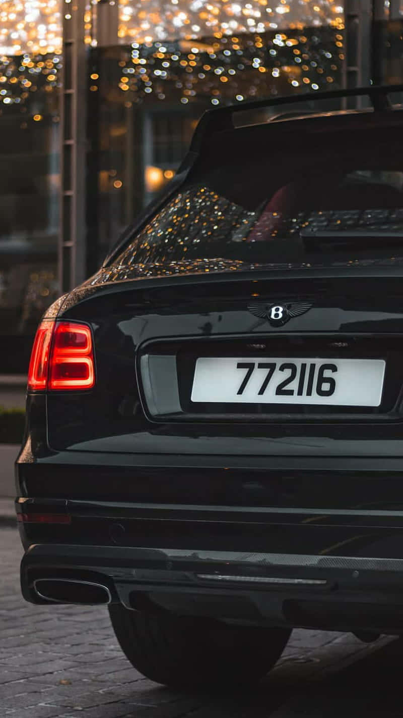 Bentley Bentayga 桌布 壁紙 — 黑色賓利Bentayga在夜晚的後視圖，背景有發光的散景燈光。