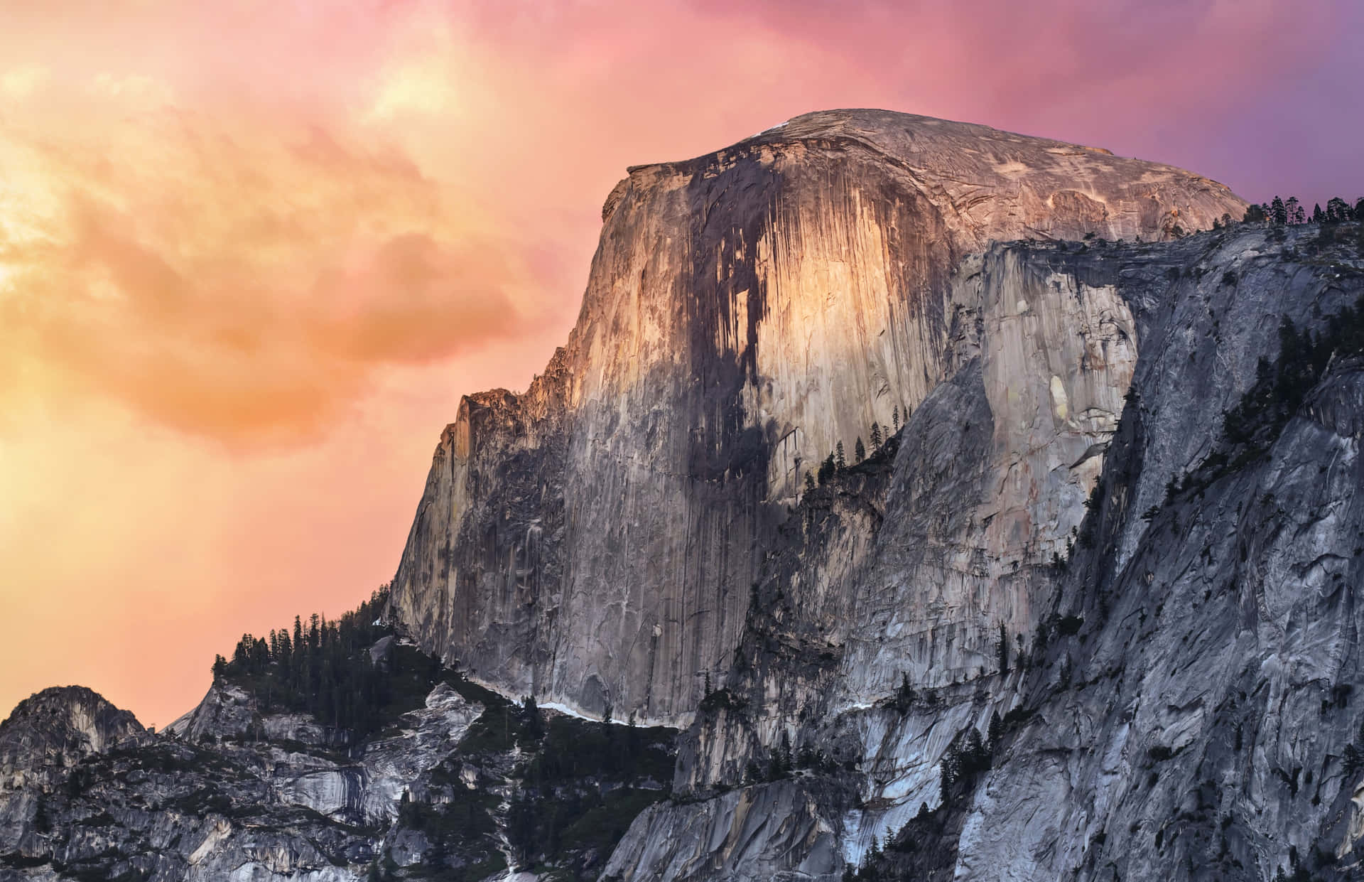 Half Dome 山沐浴在日落餘暉中，天空呈現粉紅和橙色。