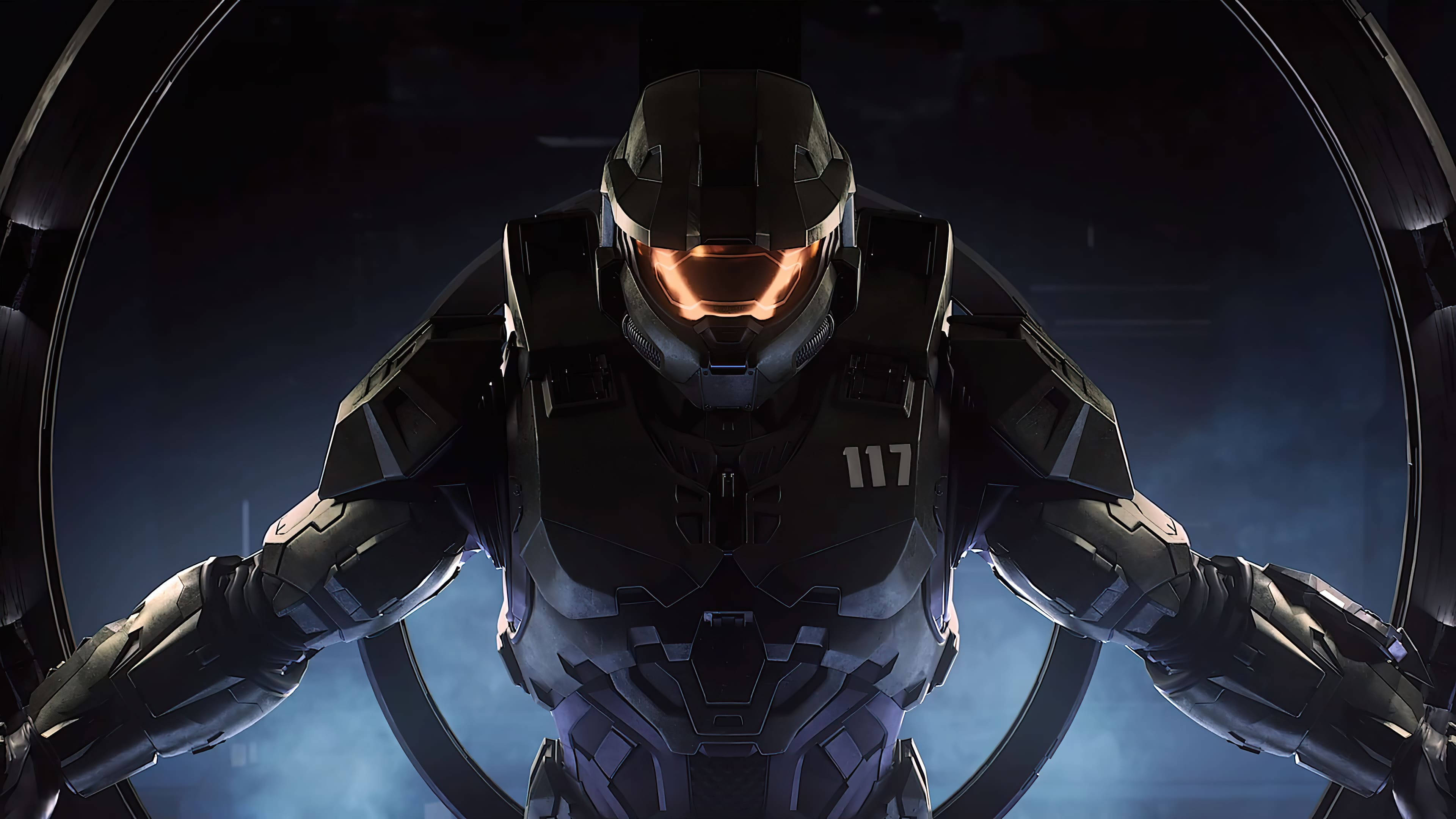 Halo Infinite 士兵 壁紙 — 一個身穿黑色盔甲、戴著發光橙色面罩的斯巴達戰士，在黑暗煙霧背景下的圓形金屬門口內威嚴地站立。