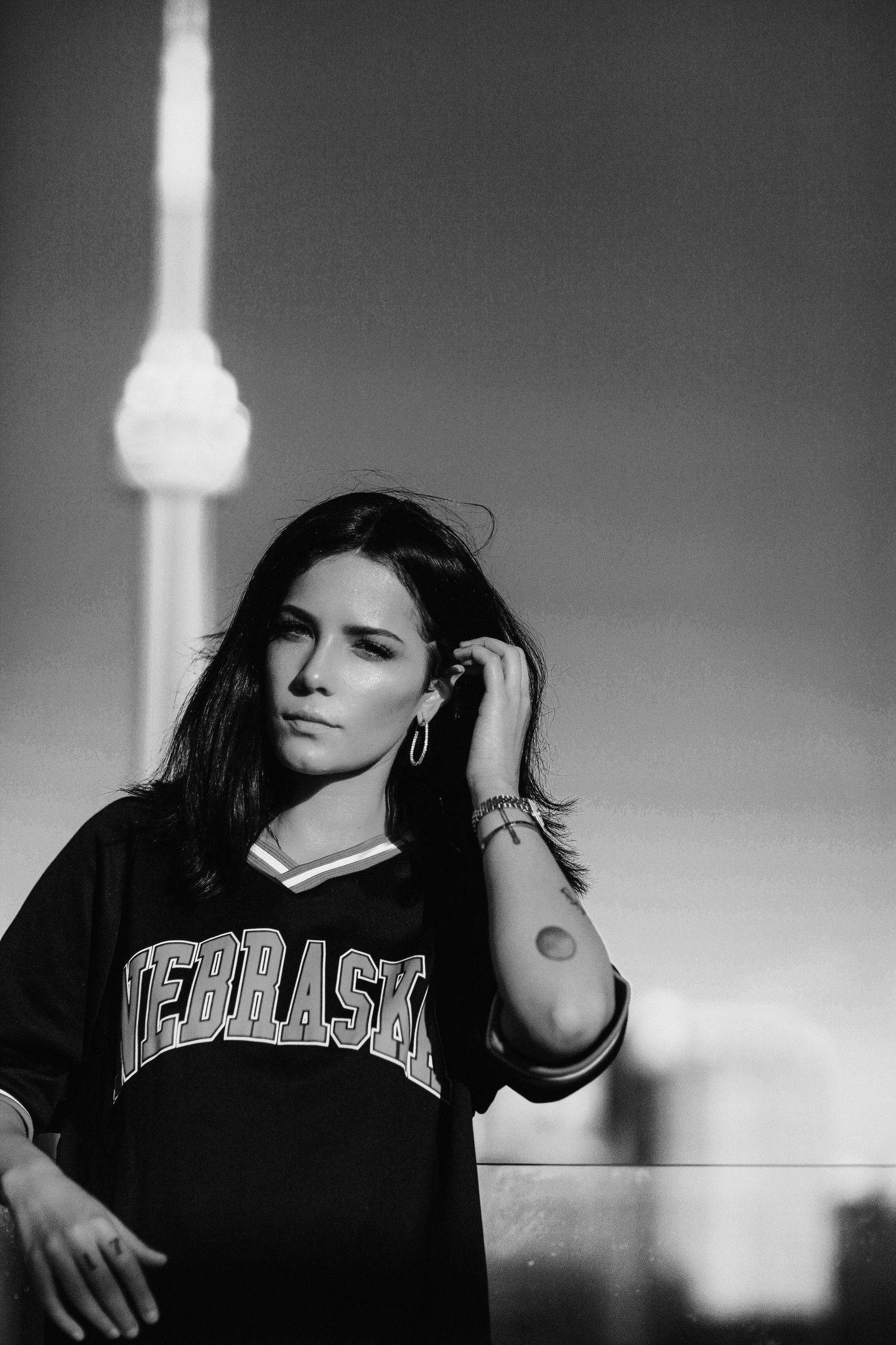Halsey 穿著印有「NEBRASKA」的黑色背心 壁紙 — 一位身穿內布拉斯加球衣的女性站在多倫多CN塔前，形成一幅引人注目的黑白城市肖像。
