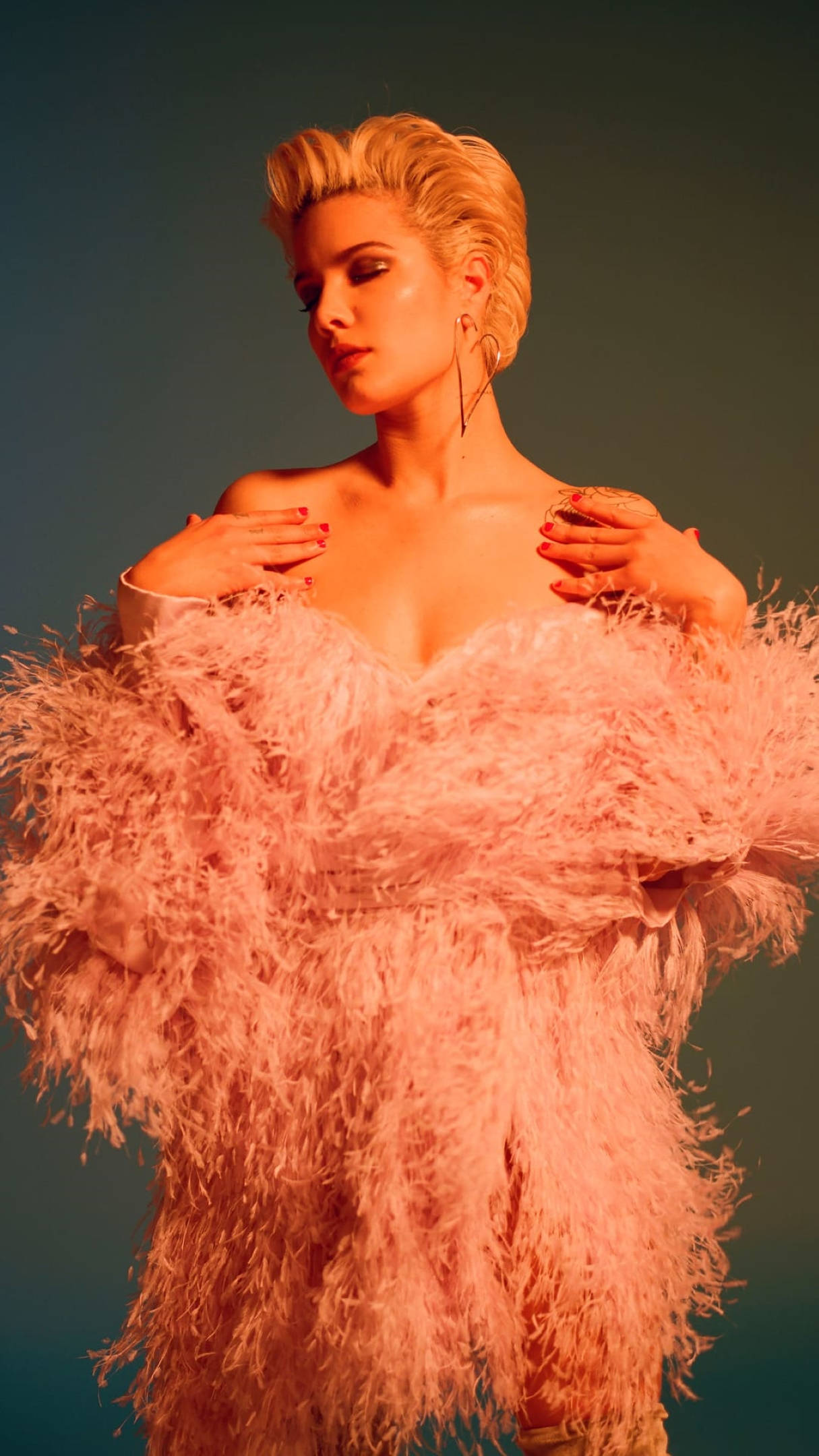 Halsey身穿桃紅色禮服 壁紙 — 一位金髮女性穿著一件蓬鬆的粉紅色羽毛連衣裙，在溫暖的燈光下以藍綠色背景為襯托。