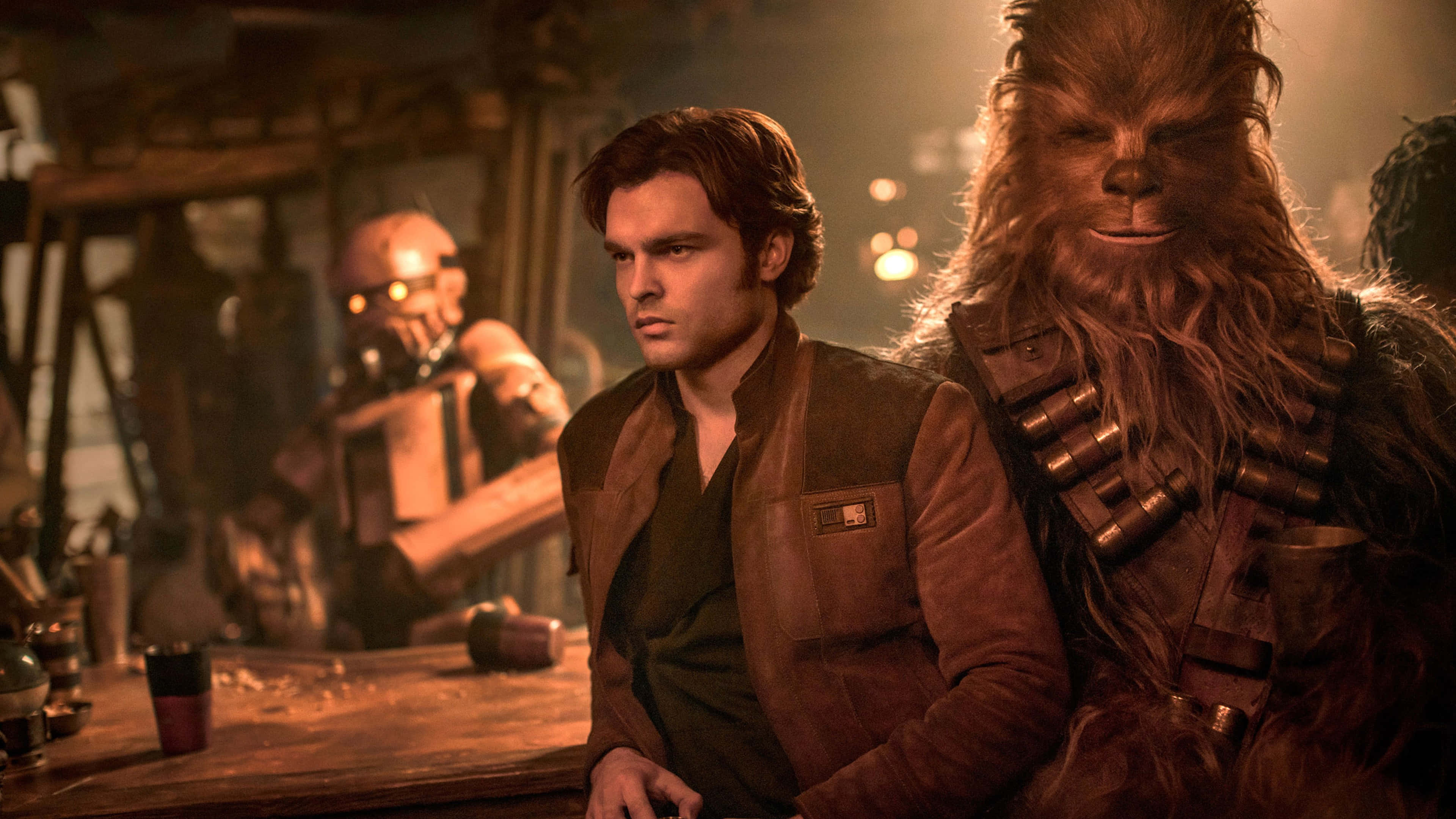 Solo A Star Wars Story 桌布 壁紙 — Han Solo 和 Chewbacca 坐在燈光昏暗的酒吧，溫暖的琥珀色燈光，背景有一個機械人。