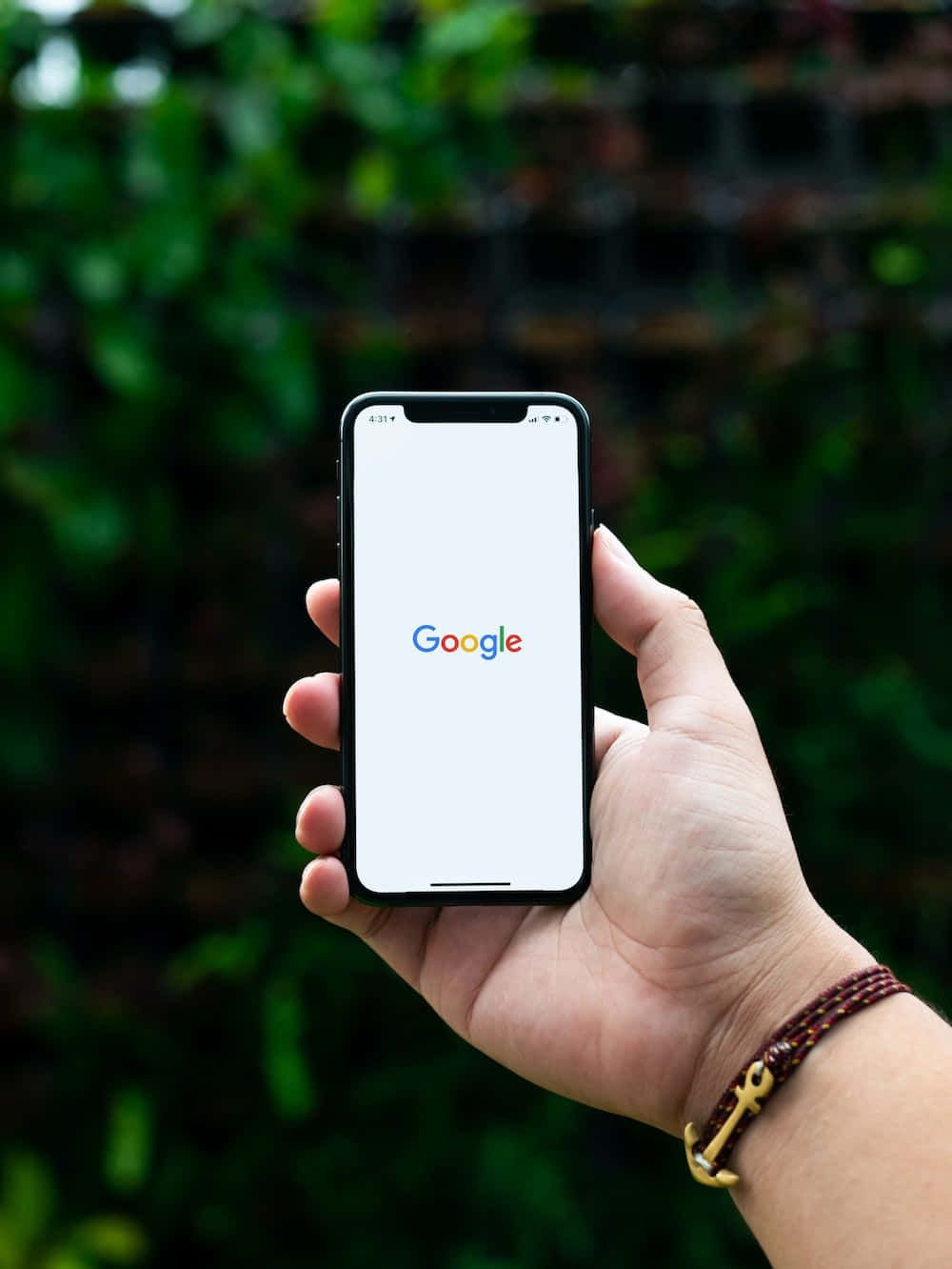 手拿著帶有Google標誌的手機，在綠色戶外環境中