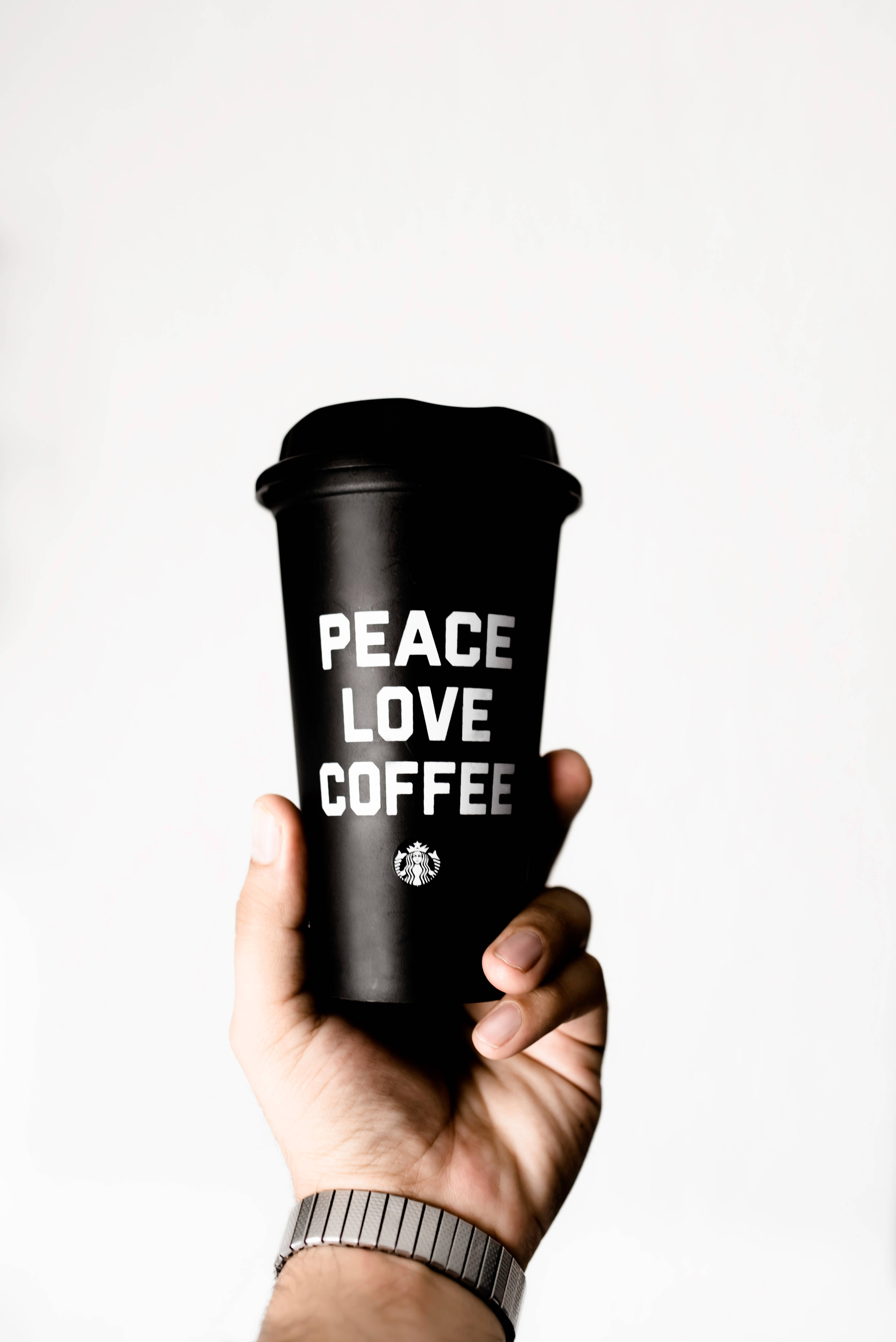 手拿著印有peace love coffee字樣的黑色咖啡杯。
